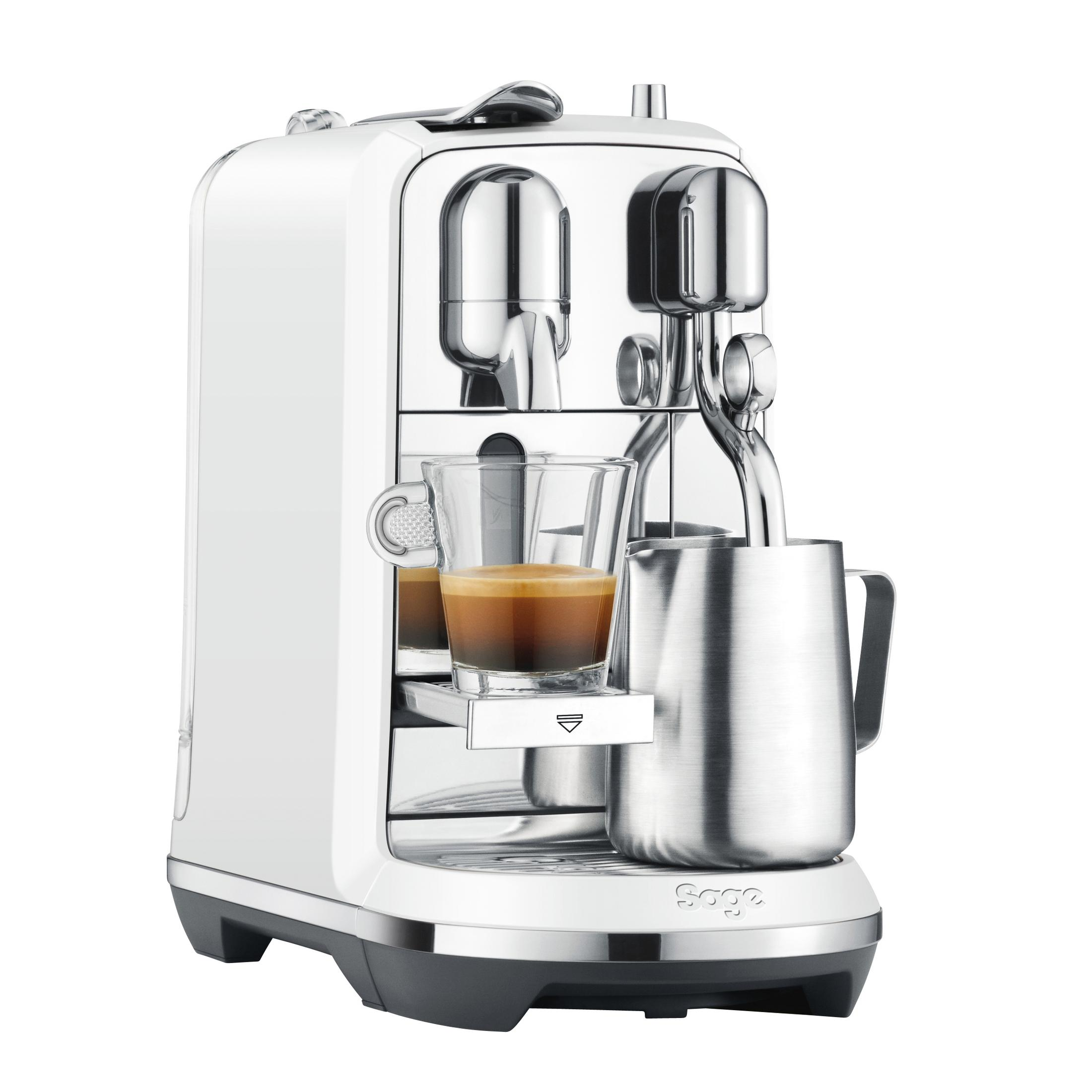Eine weiße Espressomaschine mit Chromdetails, ein Glas Espresso und ein Milchaufschäumer.