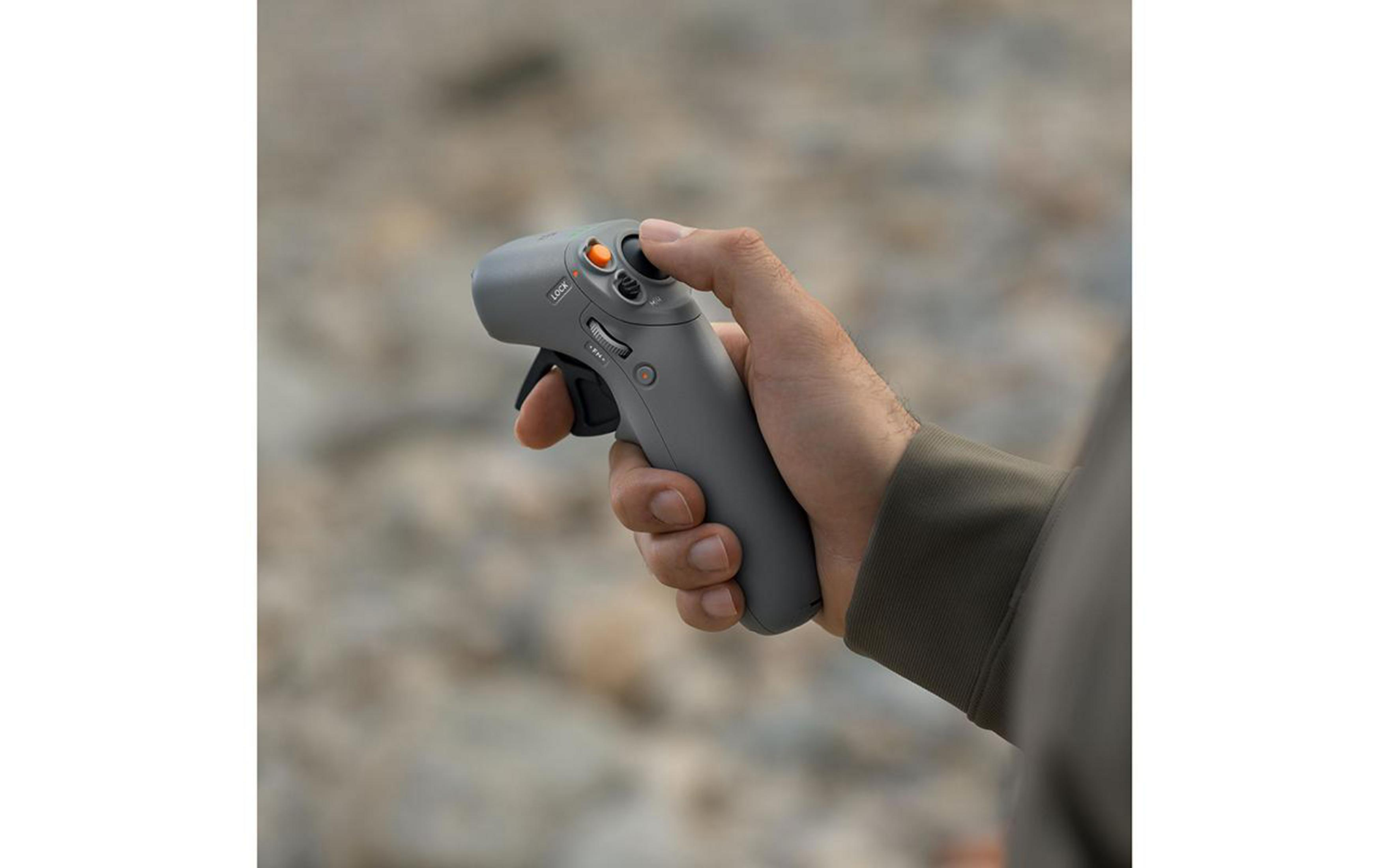 La mano de una persona sosteniendo un controlador de dron gris.