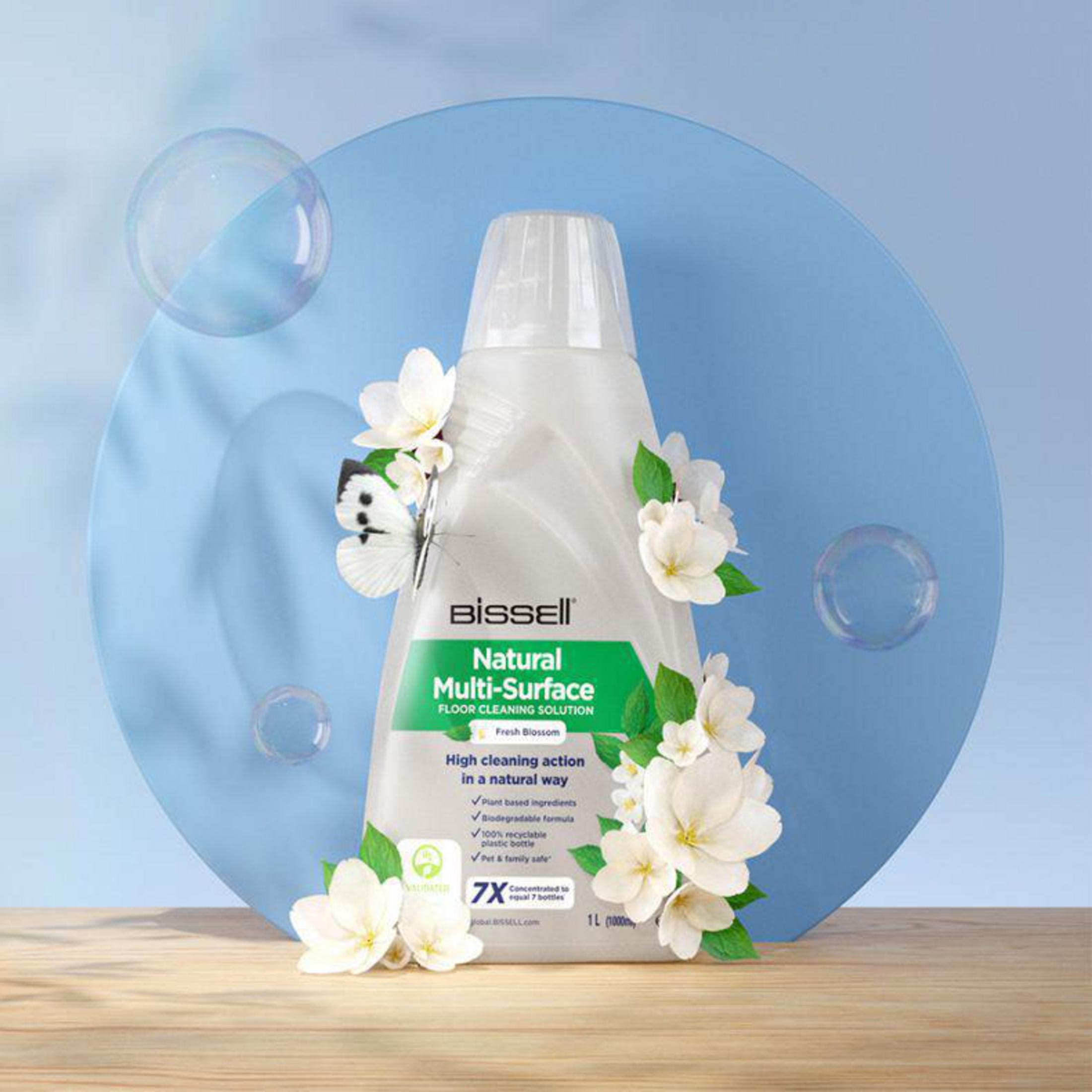 De fles reiniger staat tegen een blauwe cirkel. Bloemen en een vlinder zijn gerangschikt.