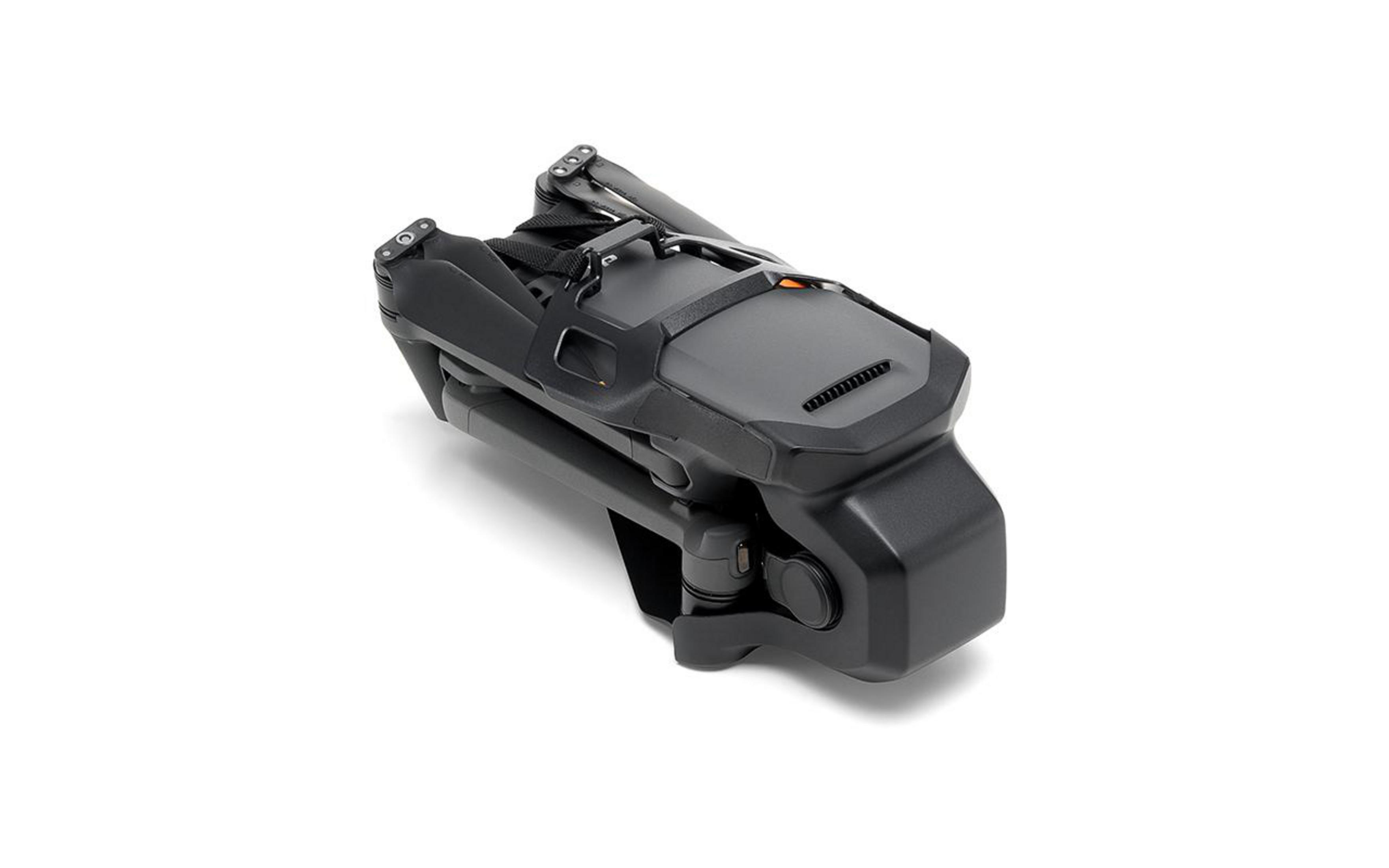 Złożony dron na białej powierzchni. Czarny korpus z szarą górą i aparatem.