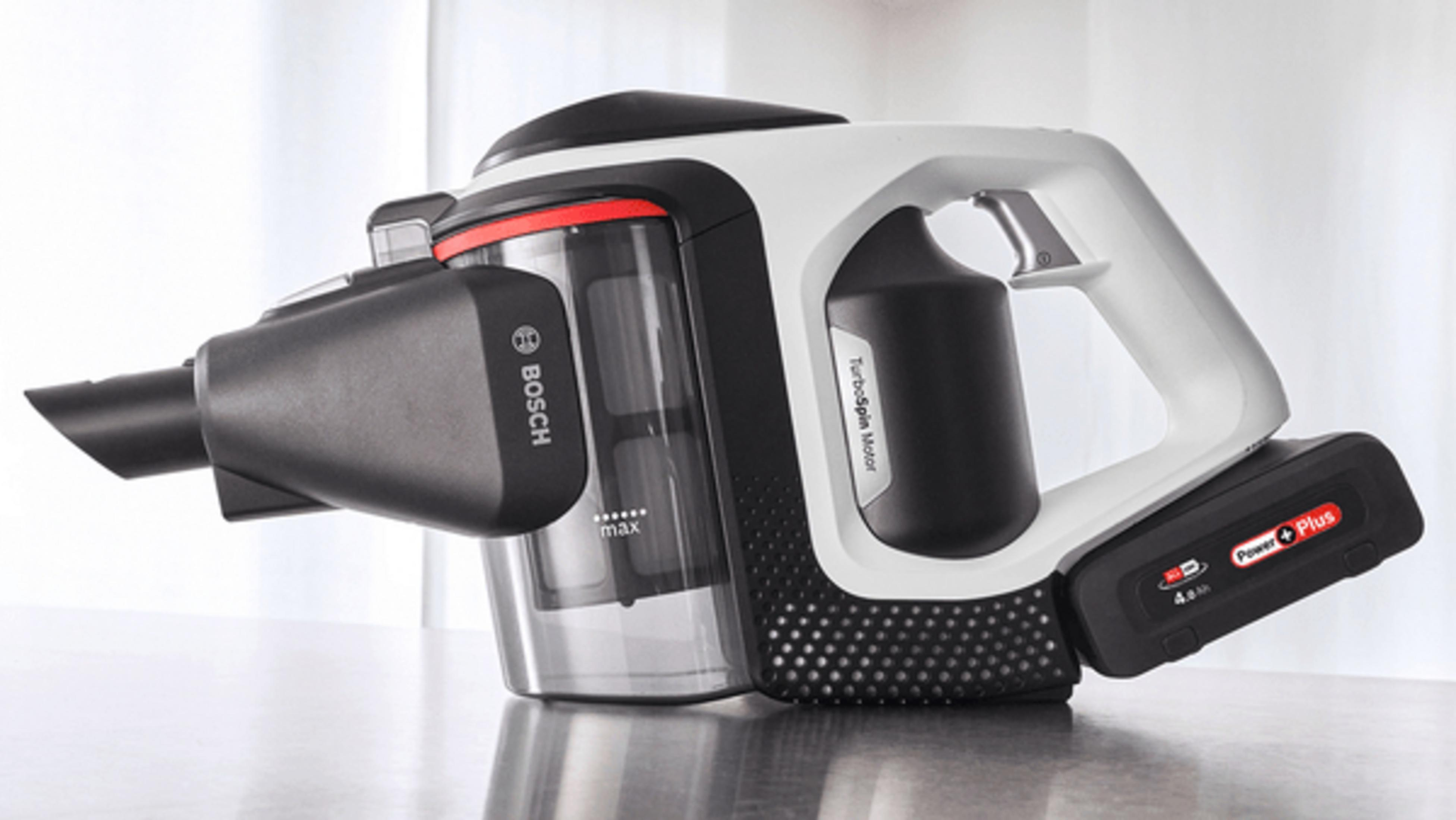 Bezprzewodowy odkurzacz Bosch, biało-czarny, z czerwonym akcentem, na szarej powierzchni. Bateria jest widoczna.