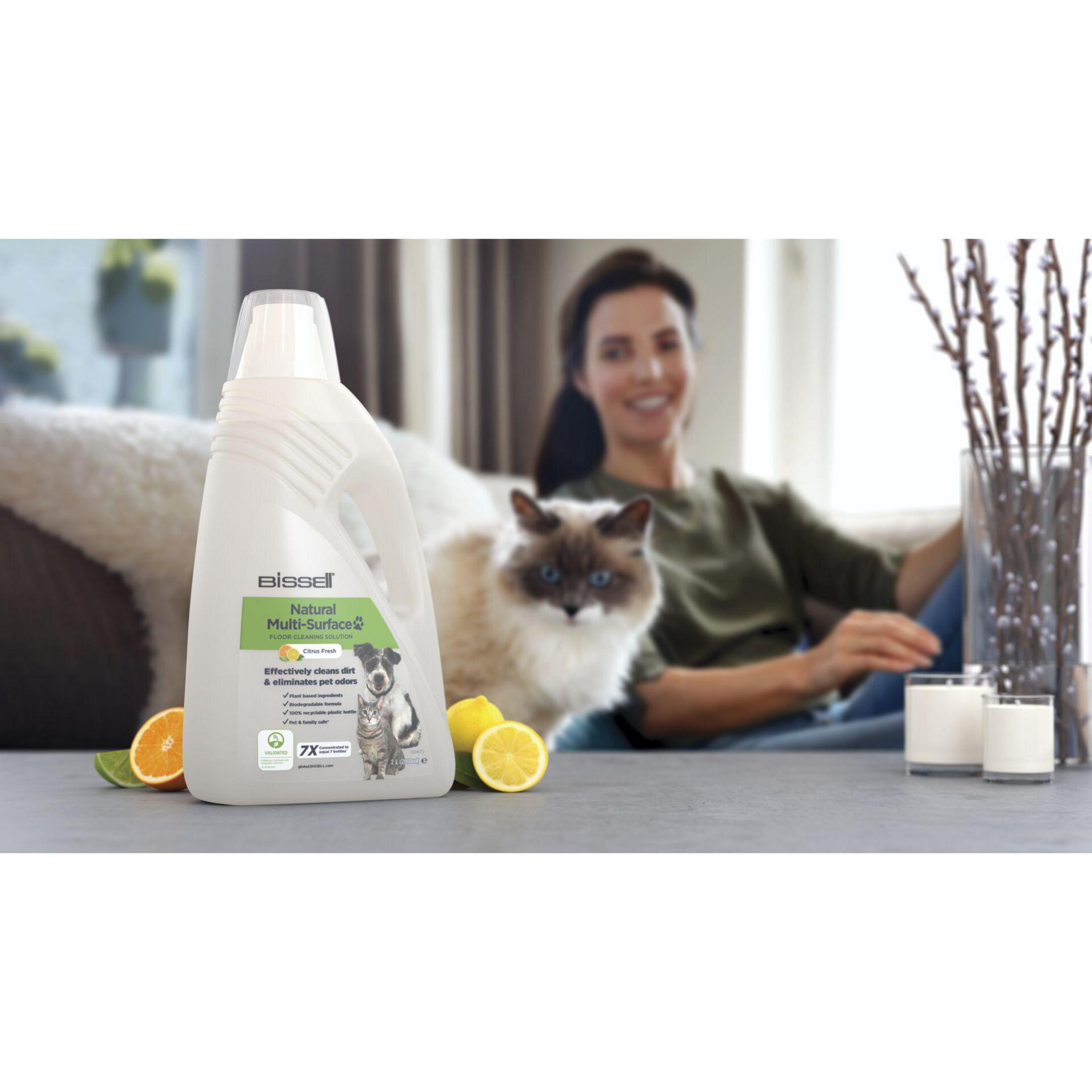 Fles schoonmaakmiddel, kat, vrouw en gesneden citroenen op tafel.