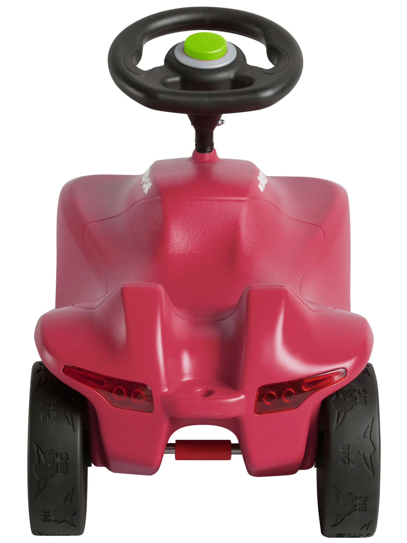 Coche de juguete rosa para montar con ruedas negras y un botón verde en el volante.
