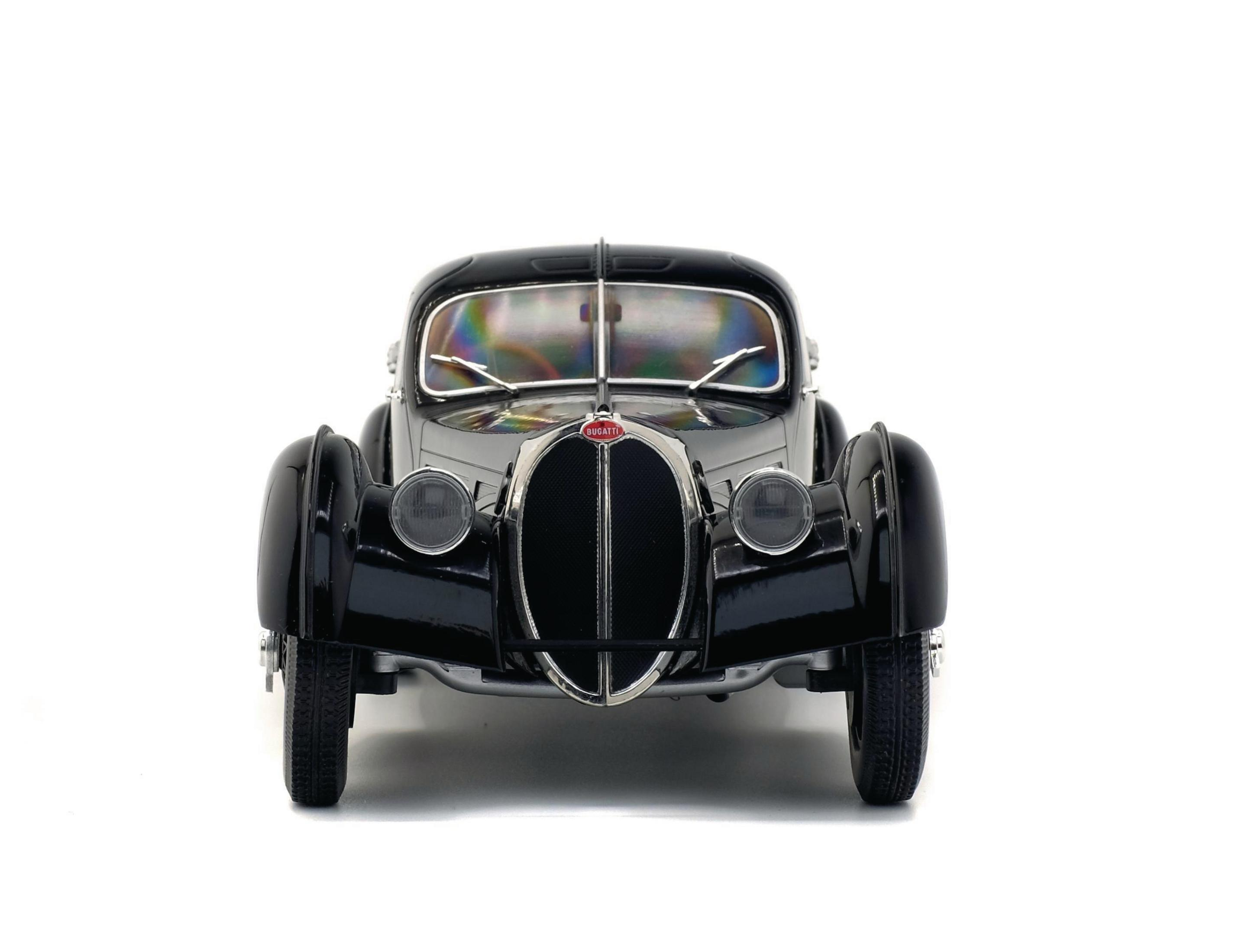 Ein schwarzes Oldtimer-Auto auf weißem Hintergrund. Das Auto wird von vorne betrachtet.