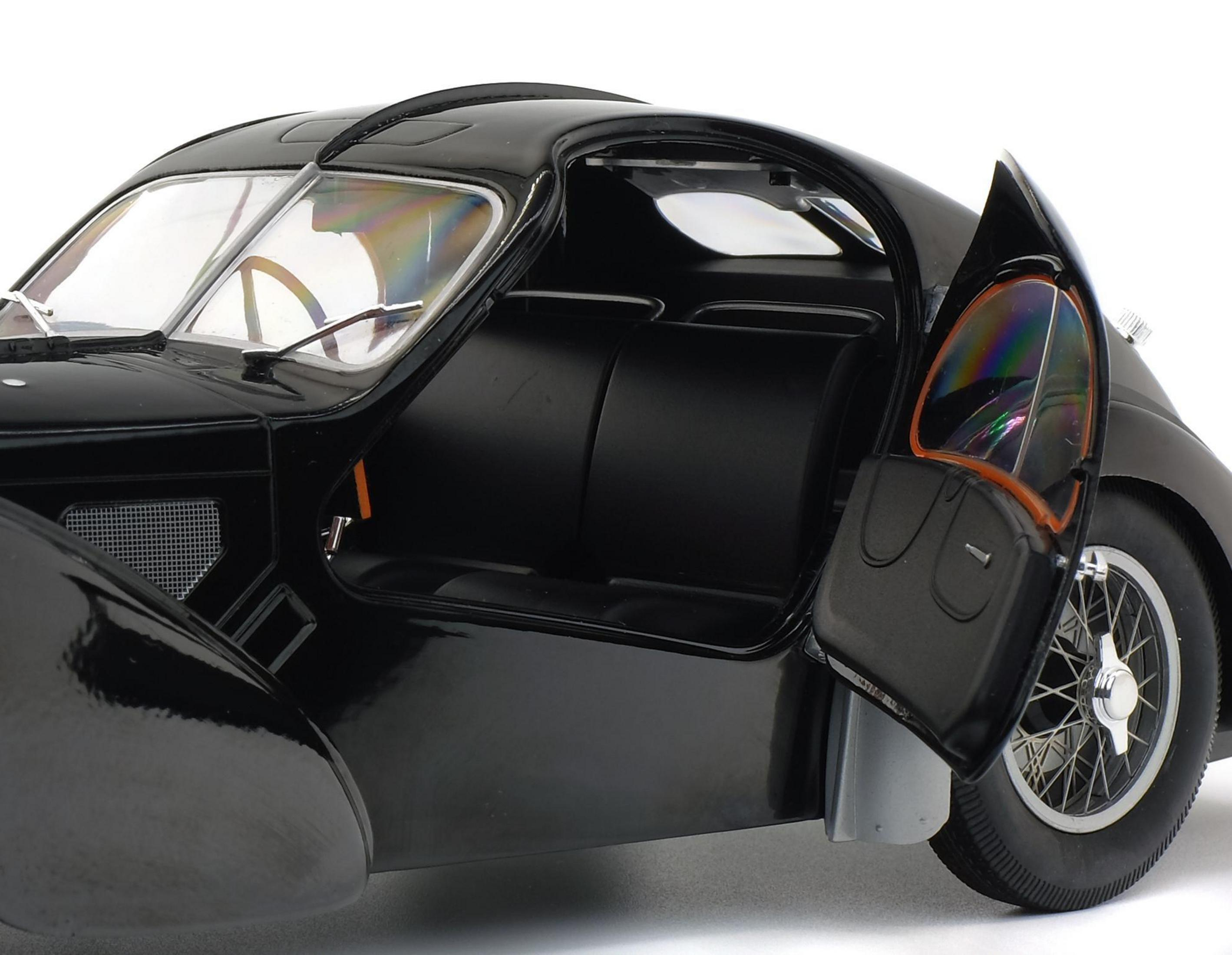 Schwarzes Oldtimer-Auto mit geöffneter Tür, Innenraum sichtbar. Weißer Hintergrund.