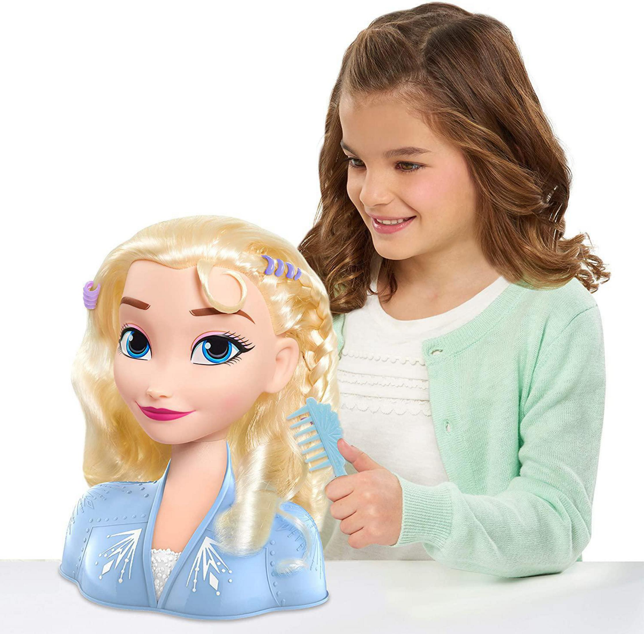 Una ragazza acconcia i capelli di una grande bambola Elsa, usando un pettine. La bambola ha la pelle chiara.