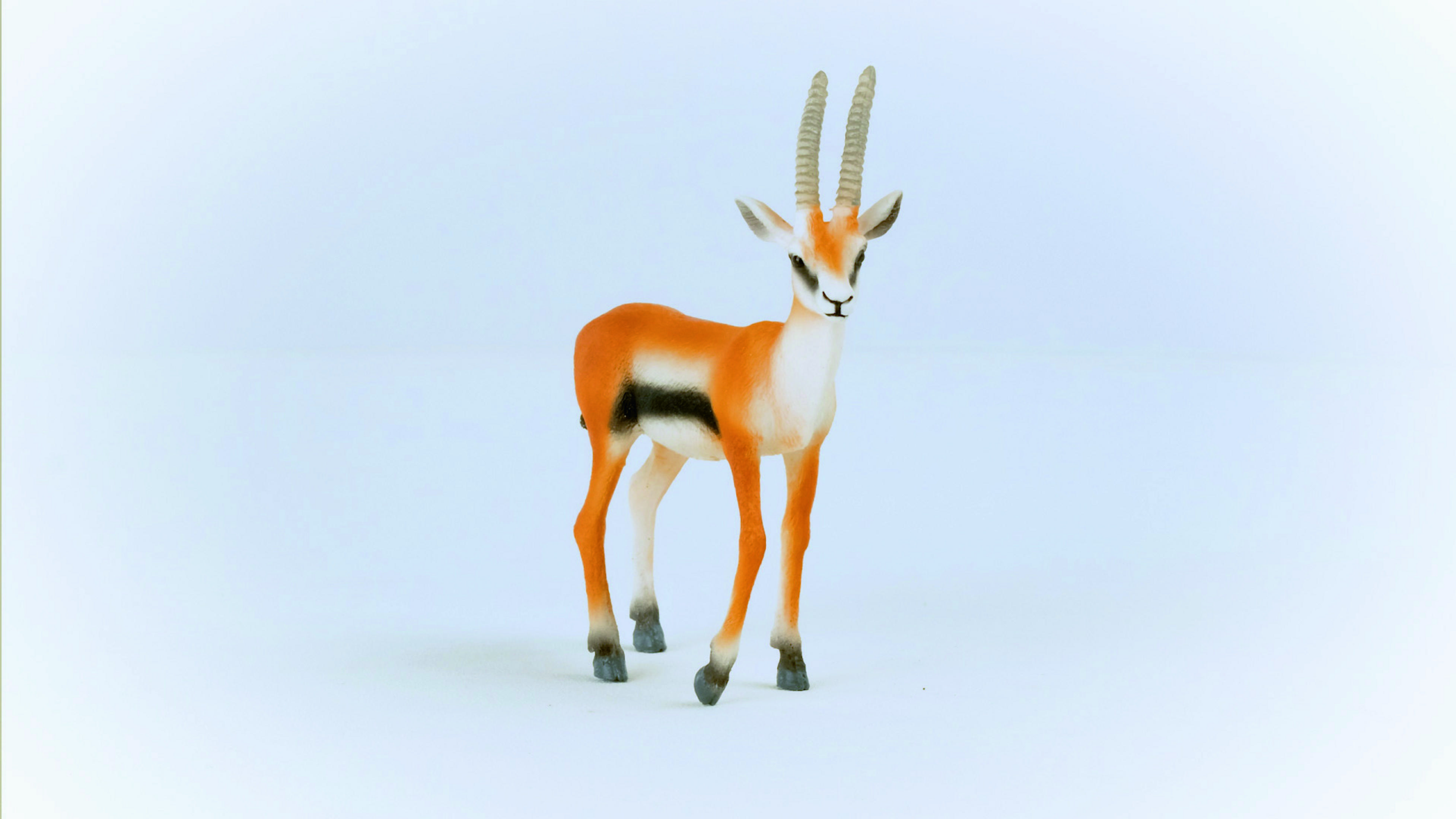 Figurka gazeli w kolorach pomarańczowym i białym. Białe tło.