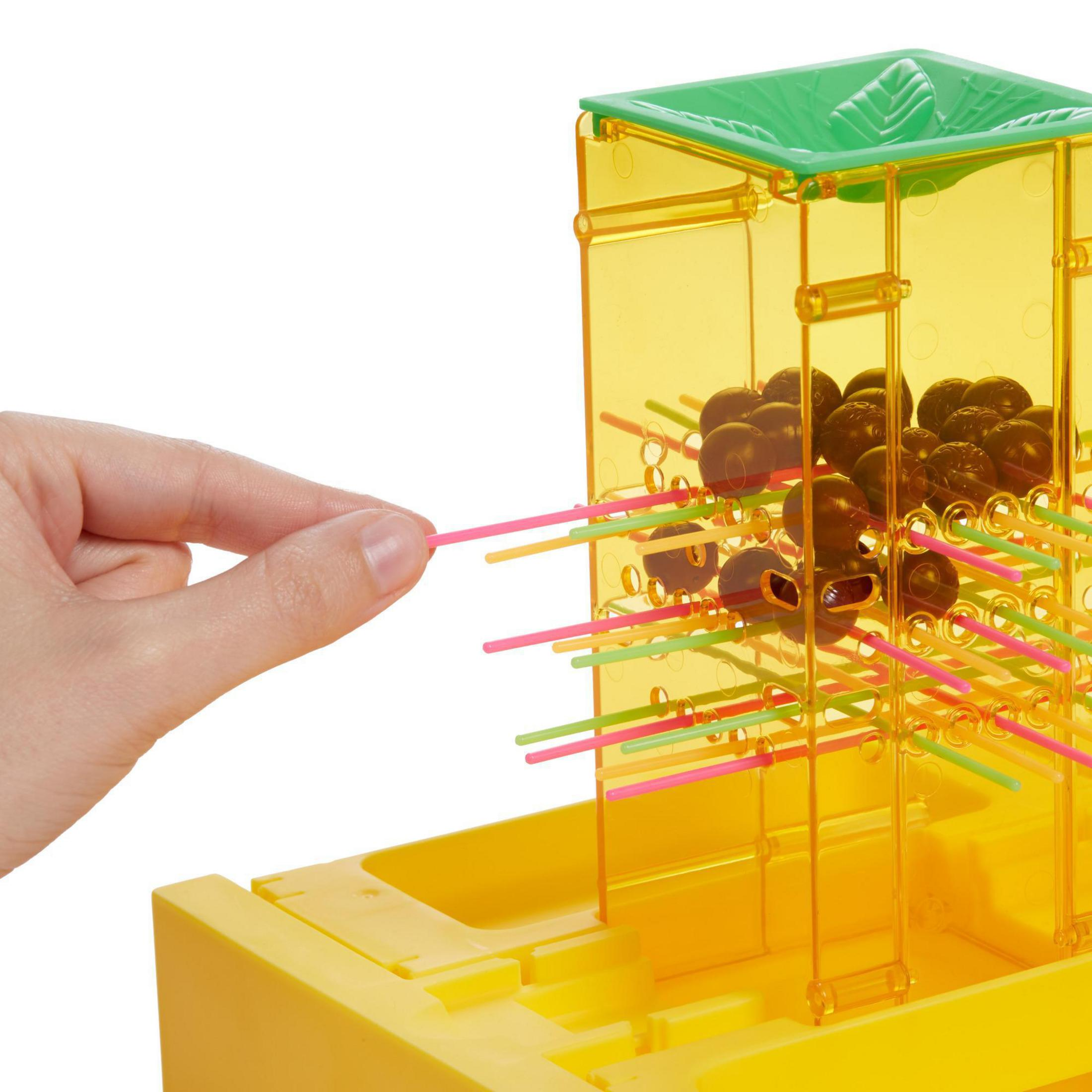 Eine Hand greift nach einem rosa Stäbchen in einem gelben und transparenten Plastikspiel.