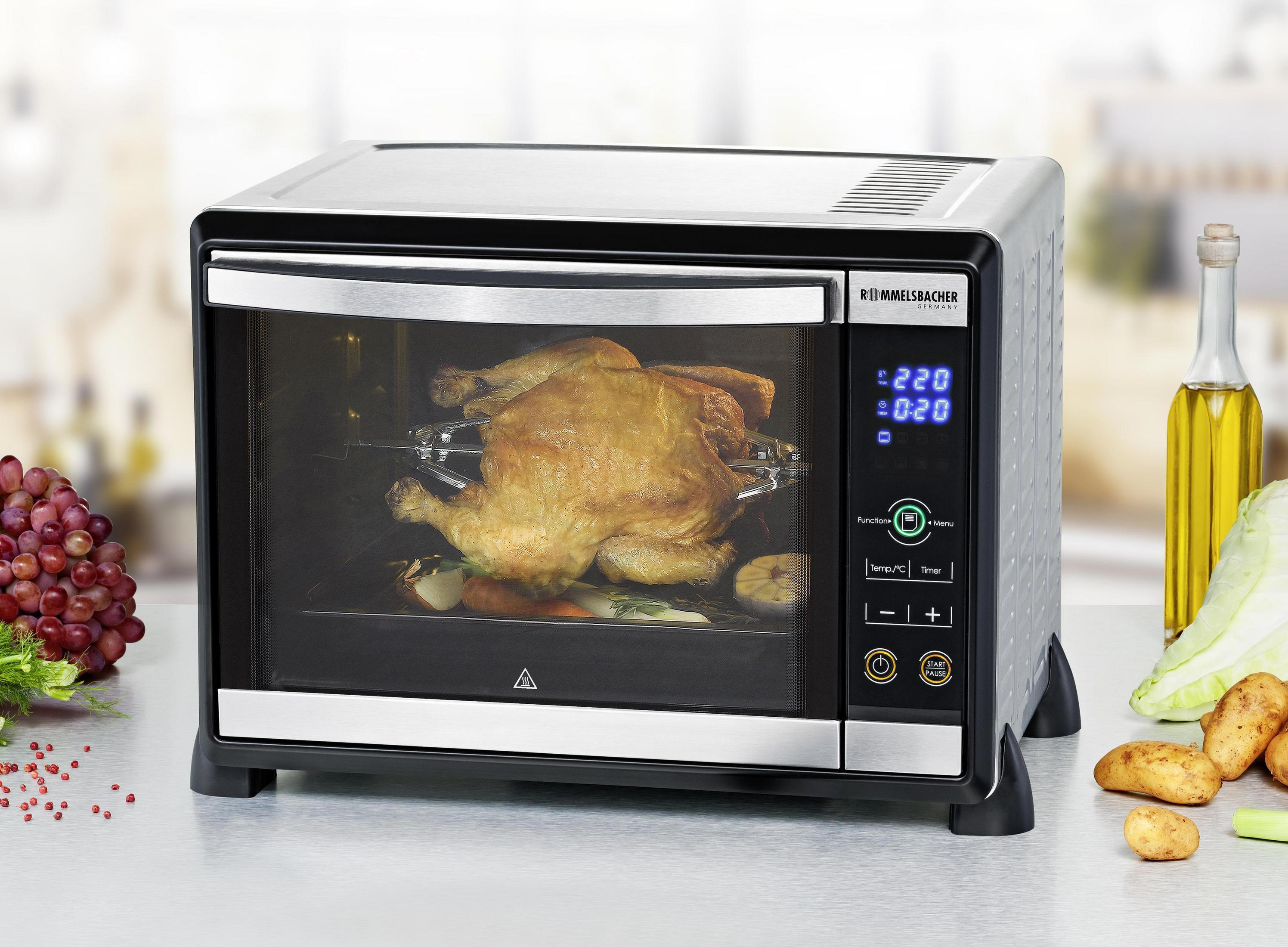 Piekarnik ze stali nierdzewnej i czarny z pieczonym kurczakiem w środku. Widoczny wyświetlacz cyfrowy i przyciski sterowania.