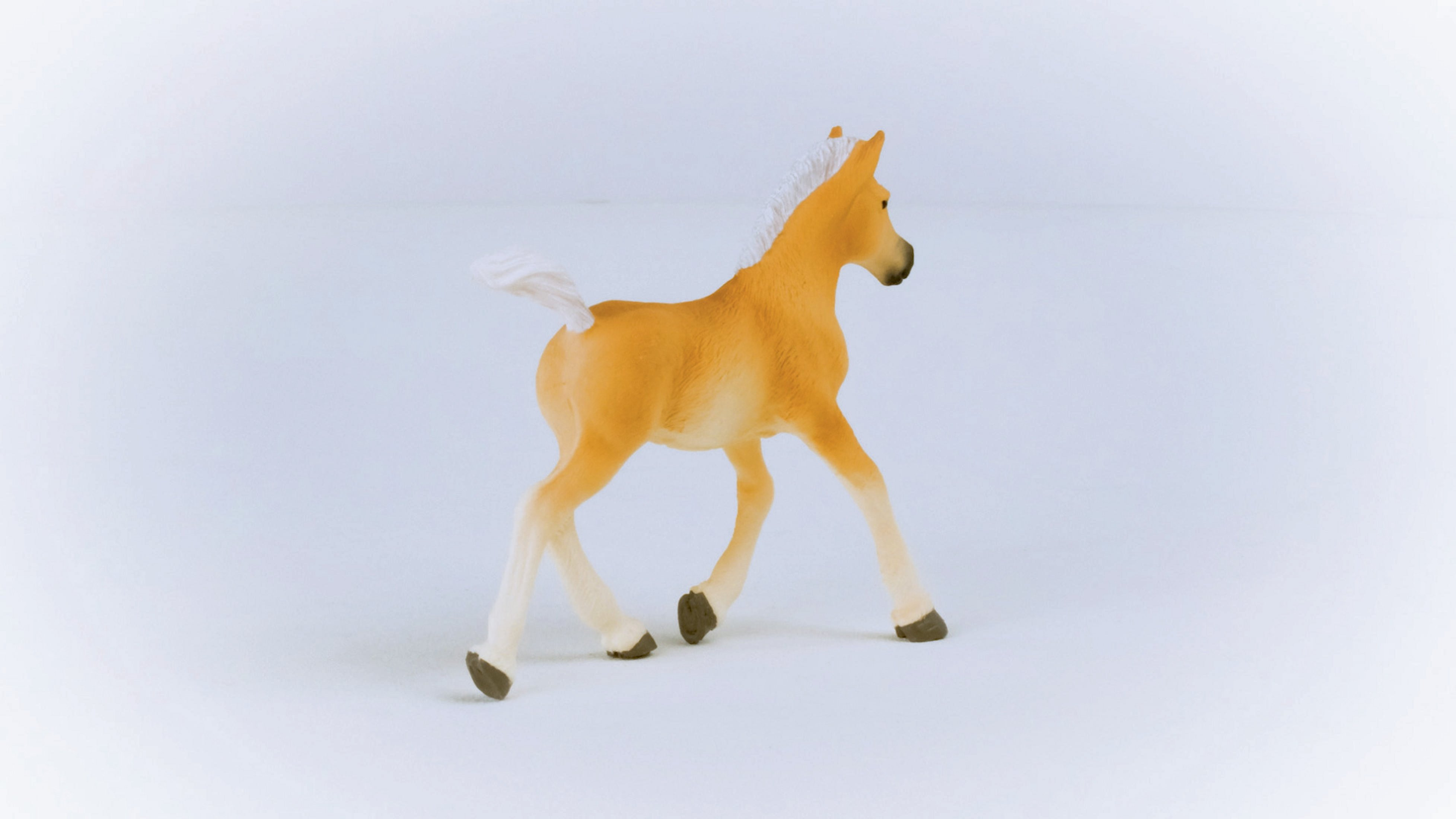 Figurka źrebaka, w kolorze brązowym z białymi nogami i ogonem. Źrebię jest obrócone w lewo.