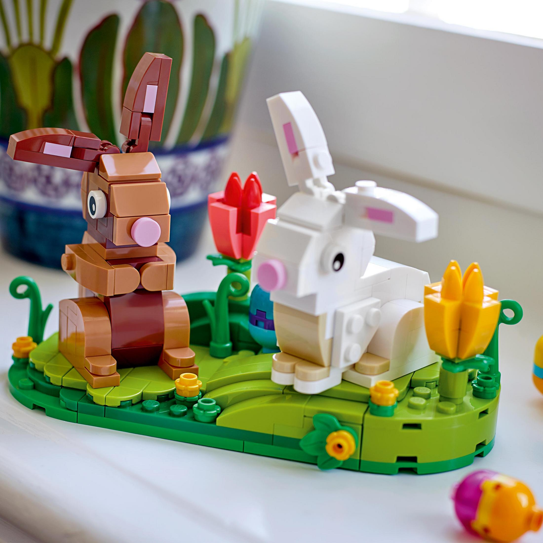 Yeşil bir taban üzerinde iki tavşan ve çiçekleri tasvir eden Lego seti. Arka plan bulanık.