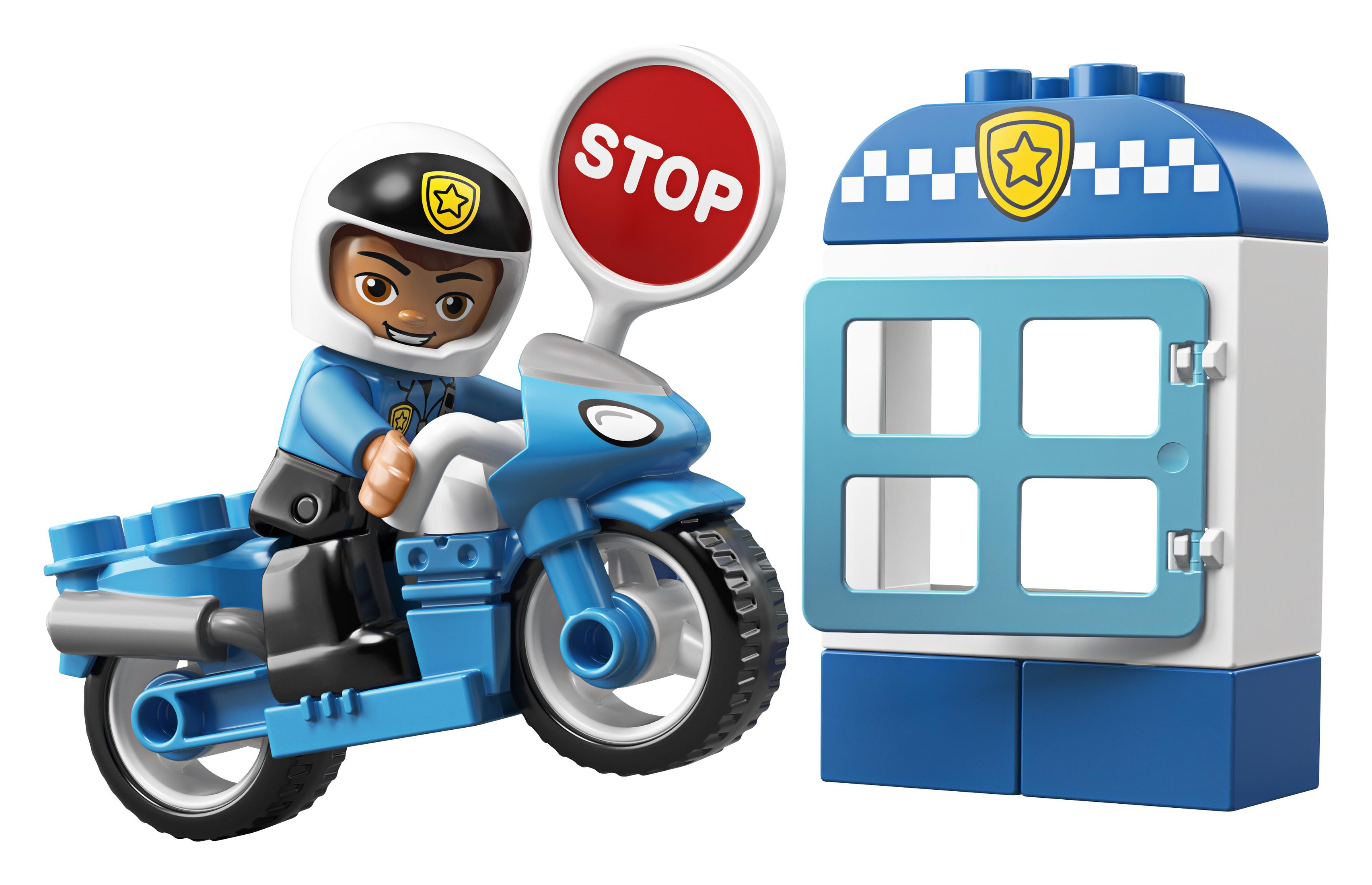 Lego Duplo Polizist auf blauem Motorrad, neben einem Polizeistationsmodell. Stoppschild.