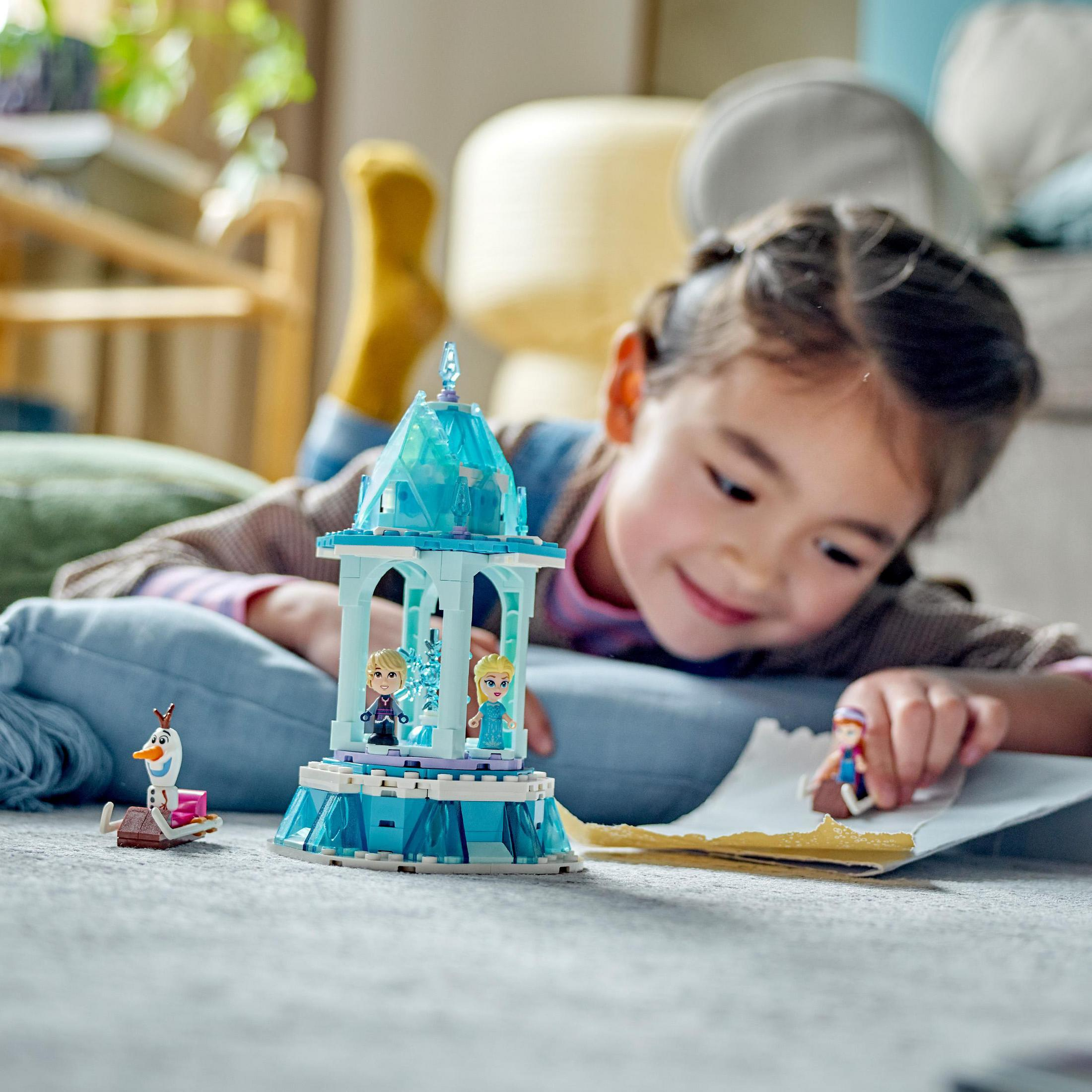 Una niña juega con un set de Lego Frozen con figuras de Elsa, Anna y Olaf en un piso azul.