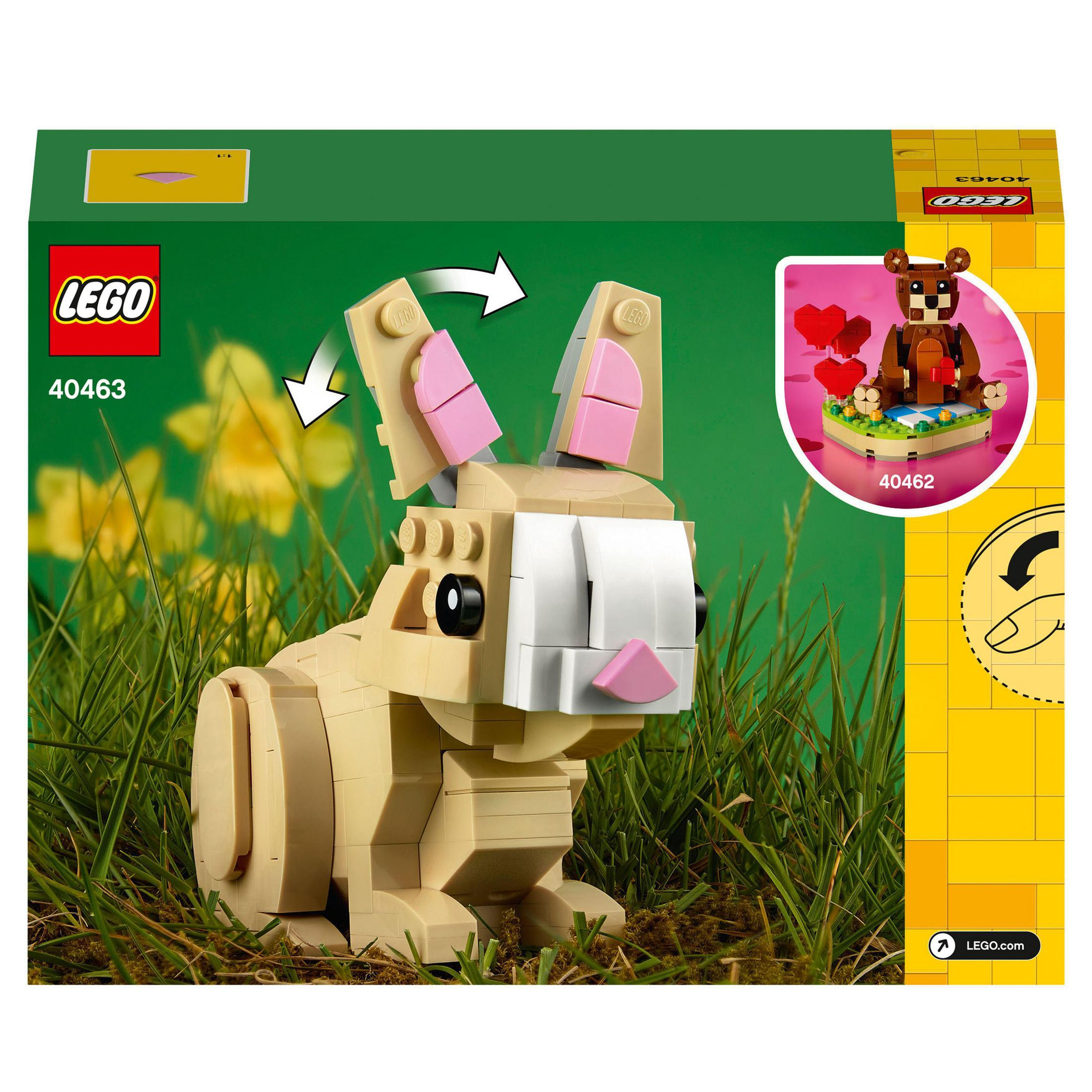 Model królika LEGO z różowymi uszami, siedzący w trawie obok pudełka ze zdjęciem misia.