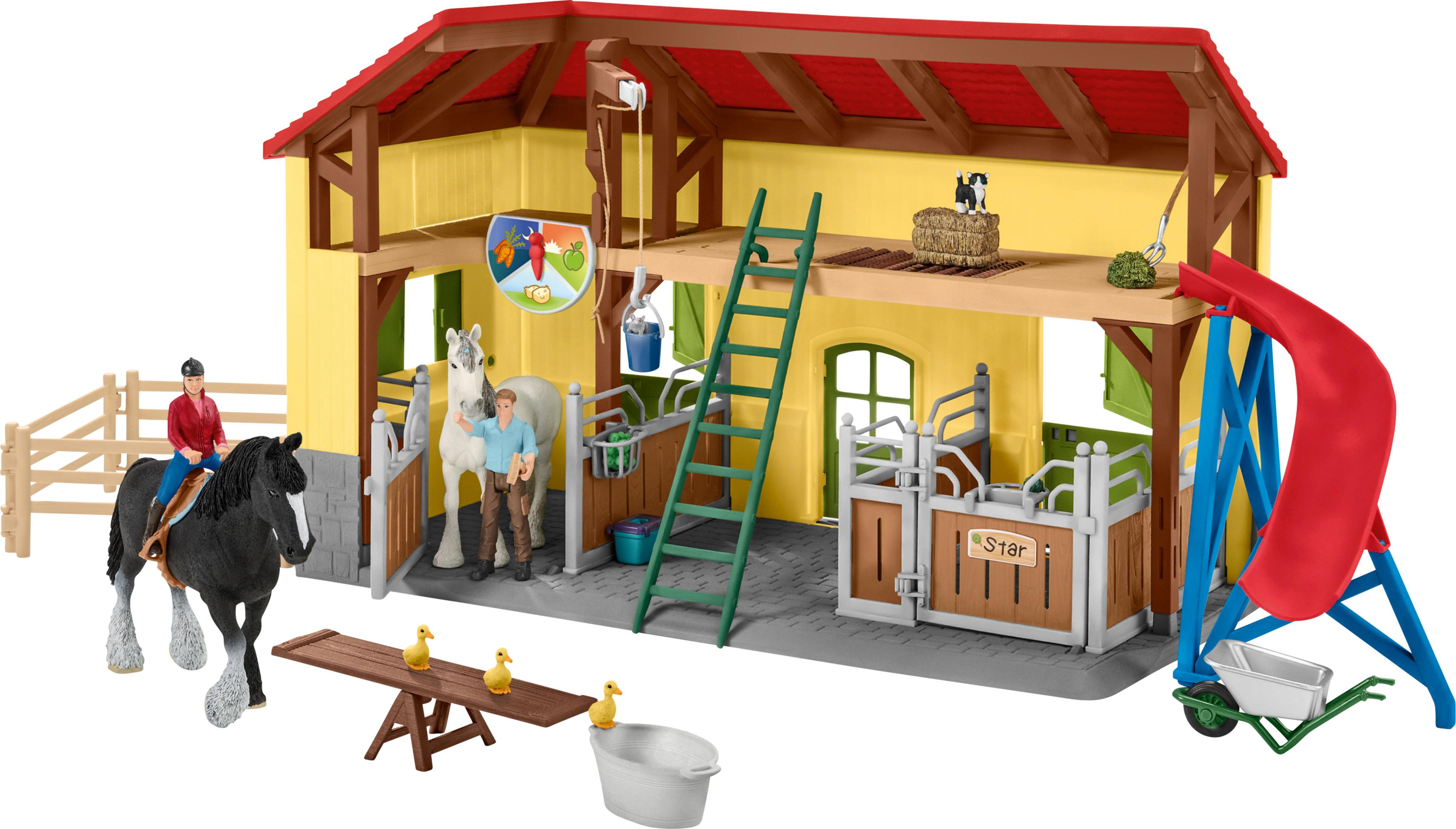 Un set di fattoria giocattolo. Un fienile giallo con tetto rosso e un playset con persone, cavalli, maiali e altri animali.