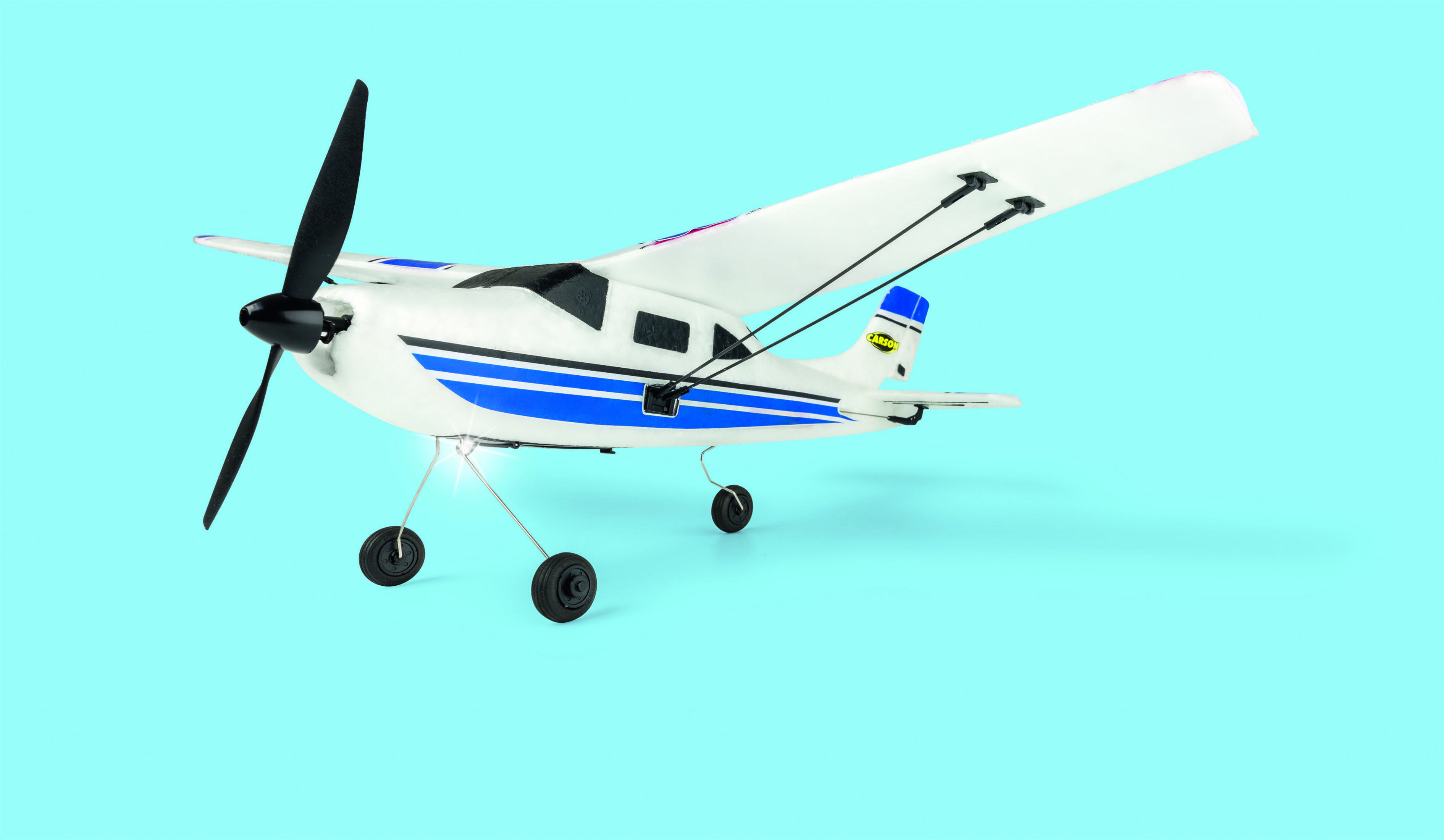 Weißes und blaues Modellflugzeug auf blauem Hintergrund mit Propeller.