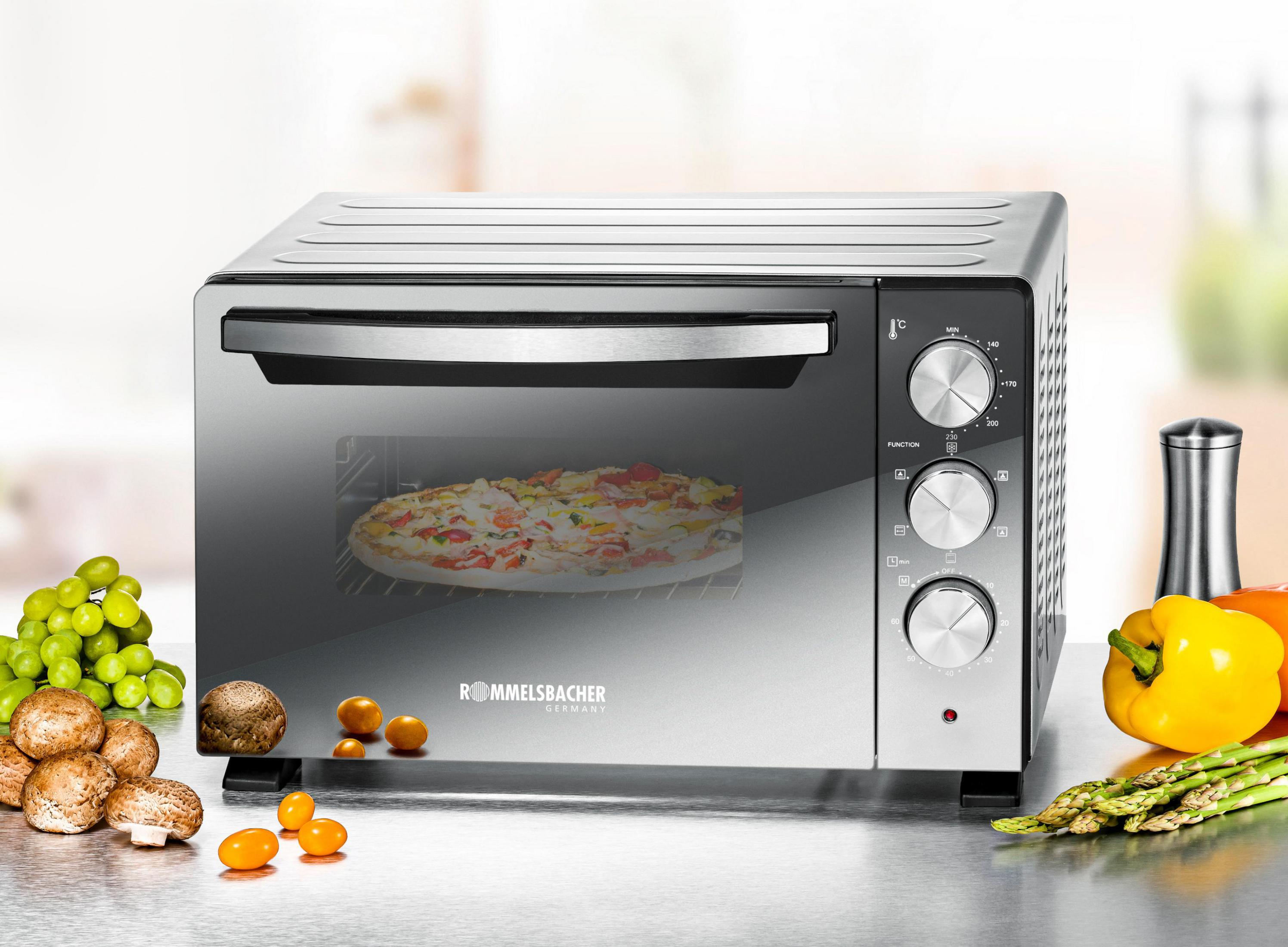 Piekarnik ze stali nierdzewnej z pizzą w środku. Na blacie znajdują się warzywa i owoce.