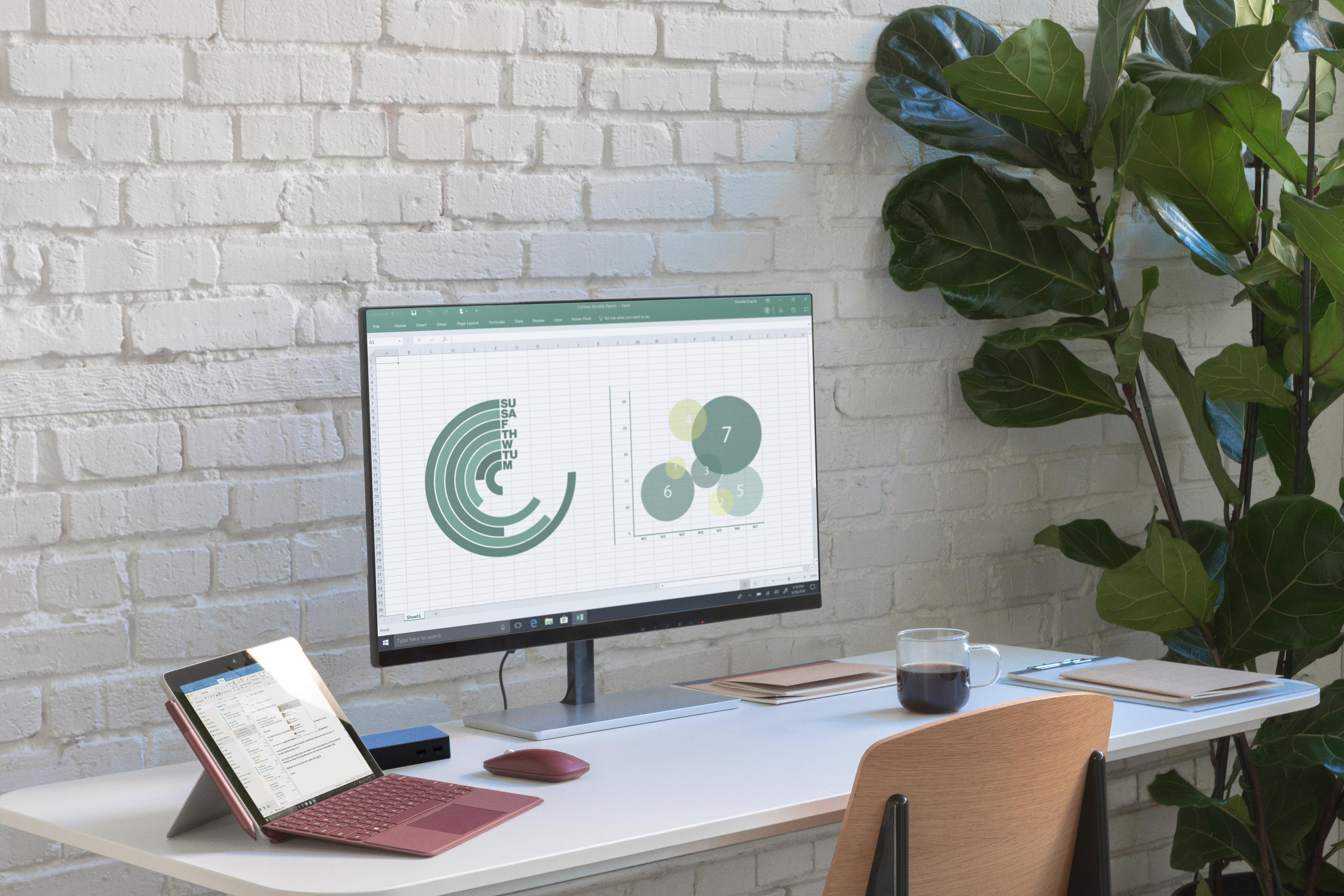 Un'impostazione moderna per l'ufficio con computer, monitor, laptop e tazza di caffè su una scrivania bianca.