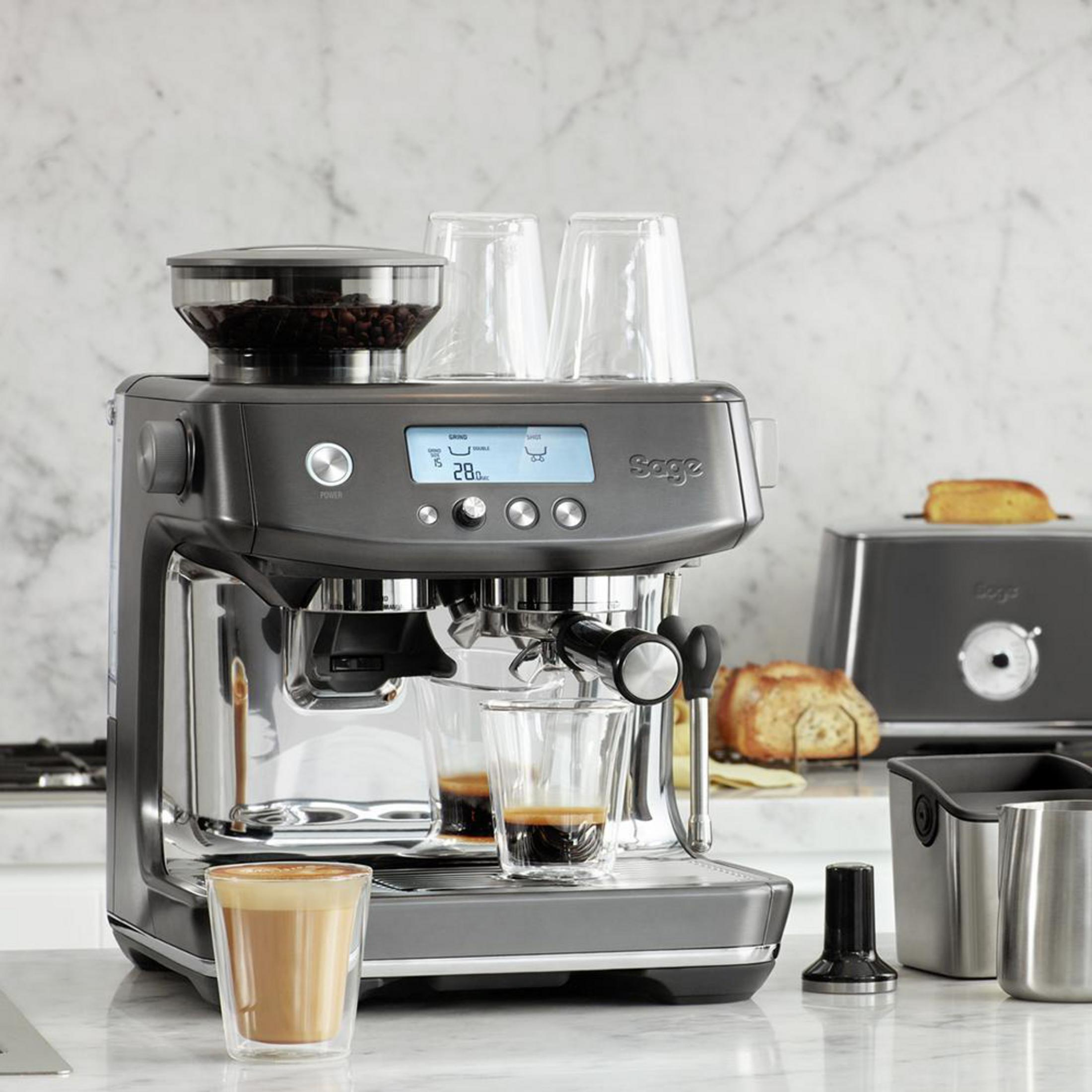 Espressomaschine mit Zubehör, ein Glas Kaffee ist fertig.