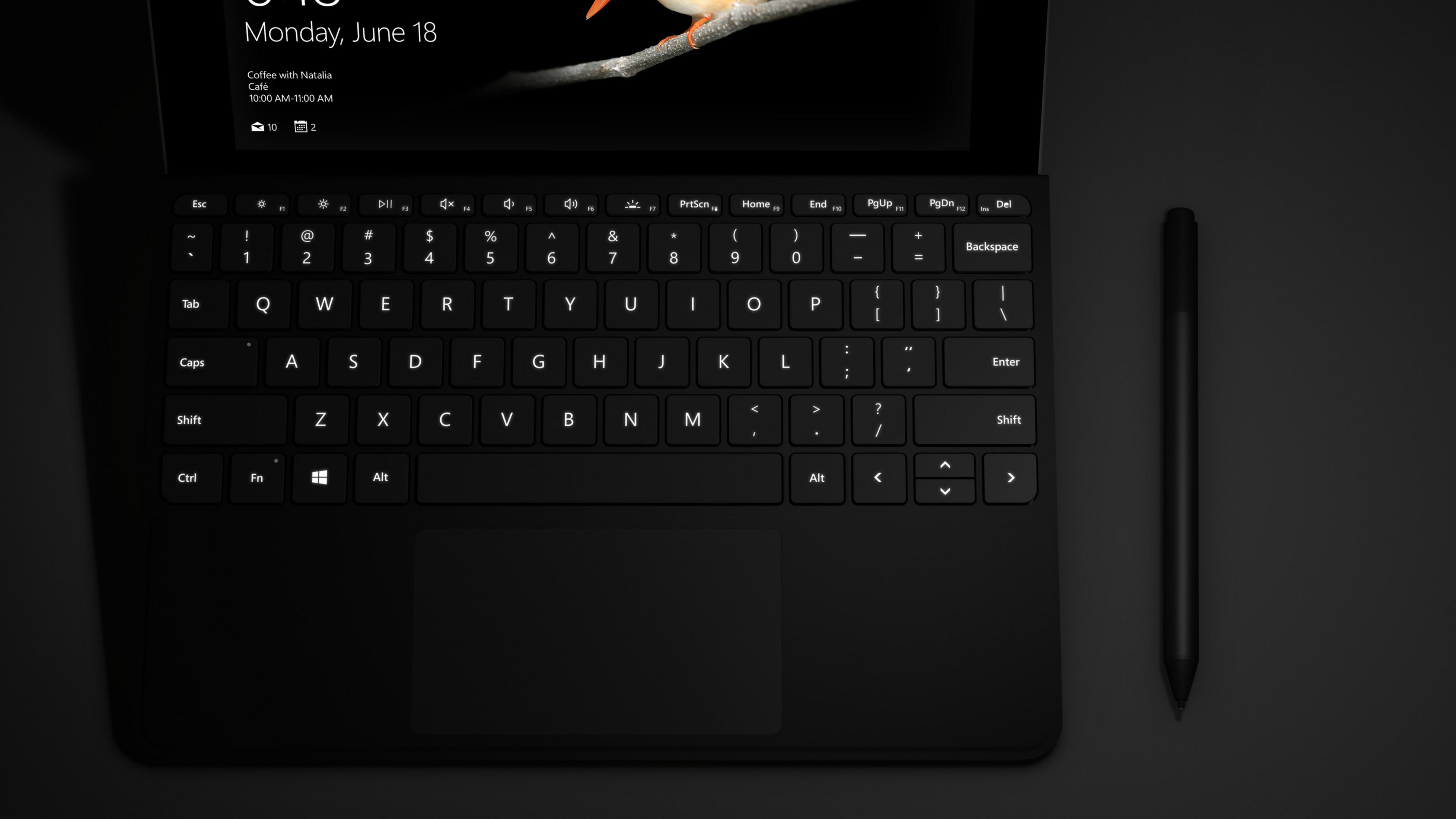 Schwarze Laptop-Tastatur mit Stift. Bildschirm zeigt einen Kalender und Zeit.