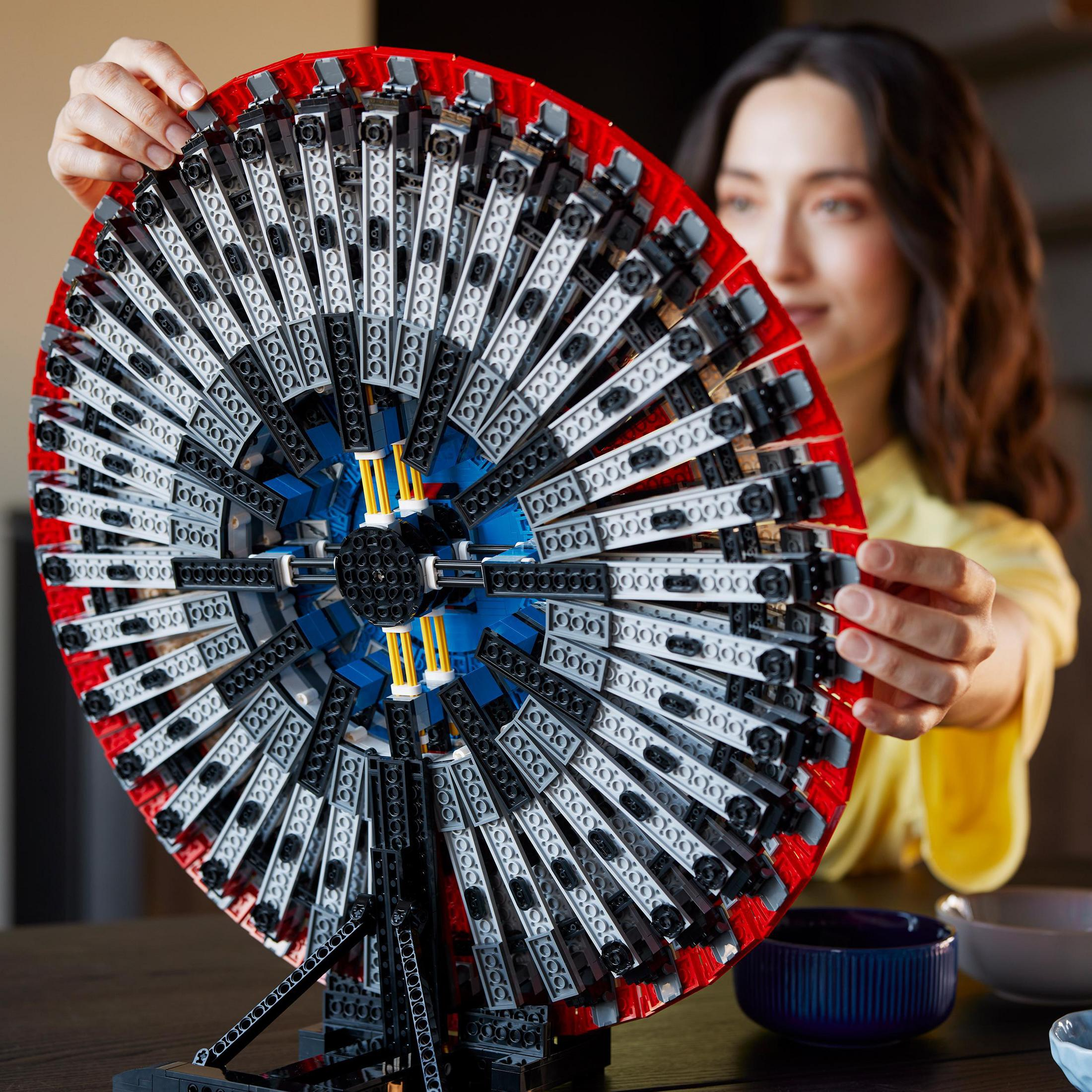 Kobieta trzymająca duży zestaw kół Lego Technic, zbliżenie.