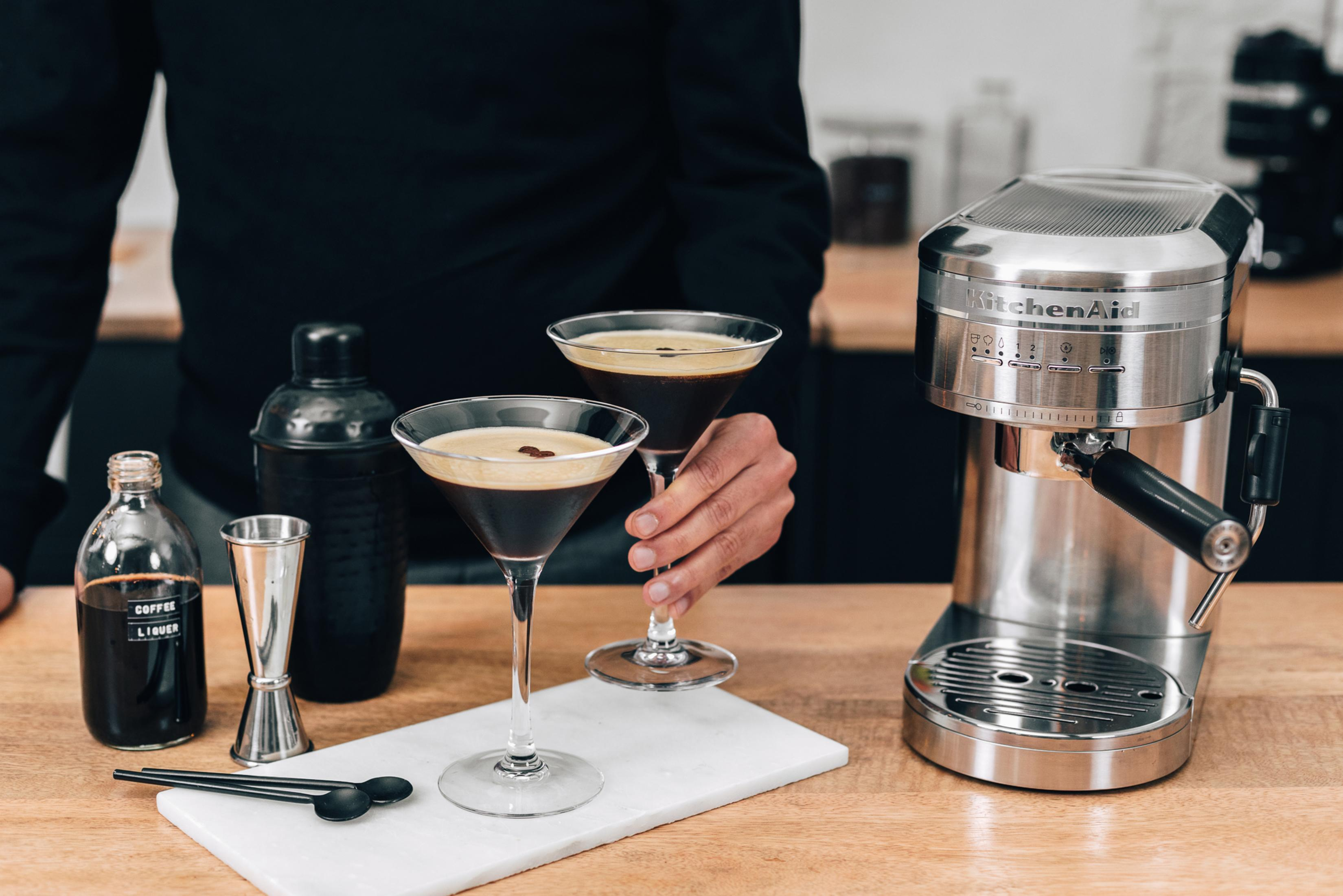 Eine Person hält zwei Espresso Martinis mit einer Kaffeemaschine.