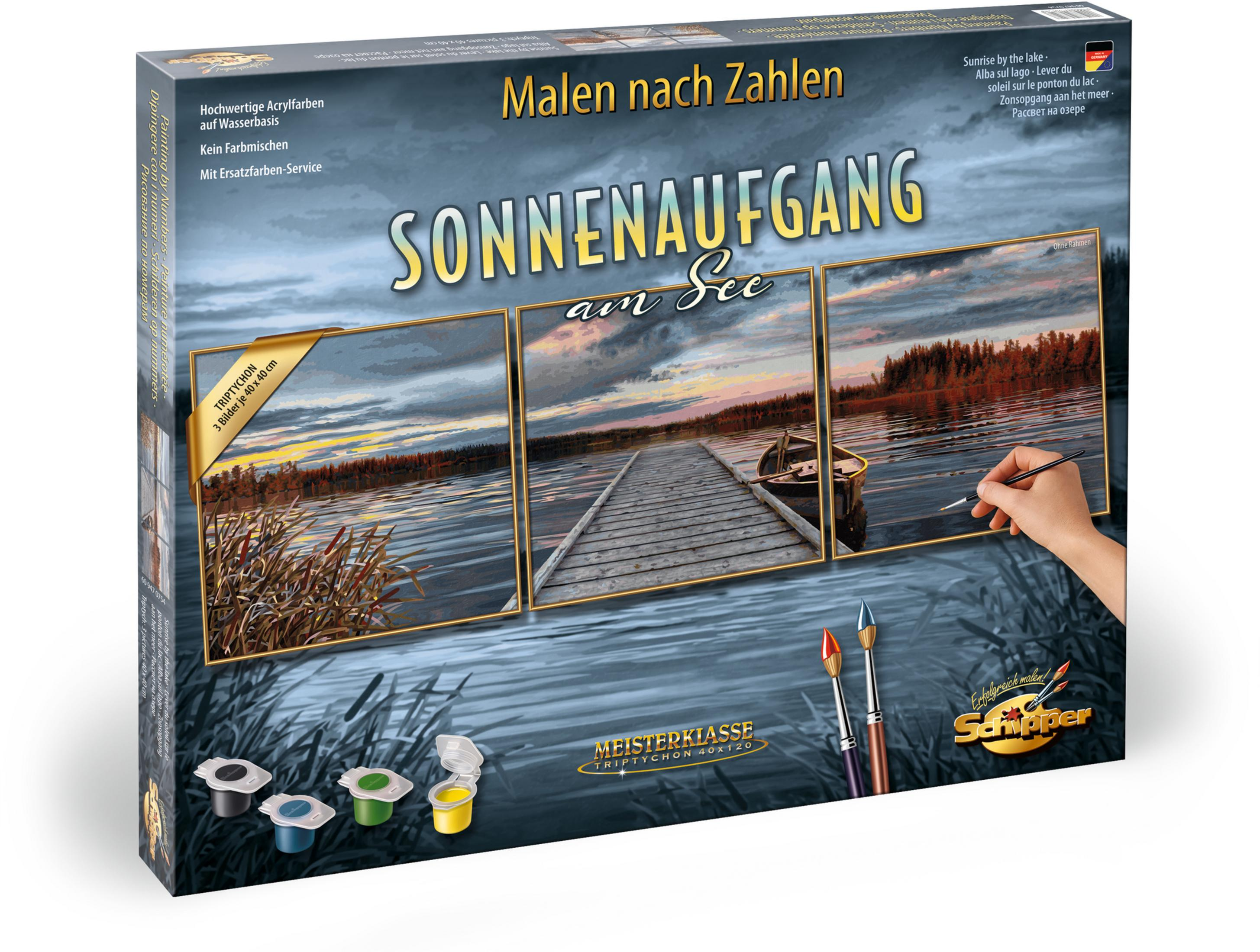 Eine Box mit einem Gemälde einer Seeszene. Farben, Pinsel und eine malende Hand sind im Bild enthalten.