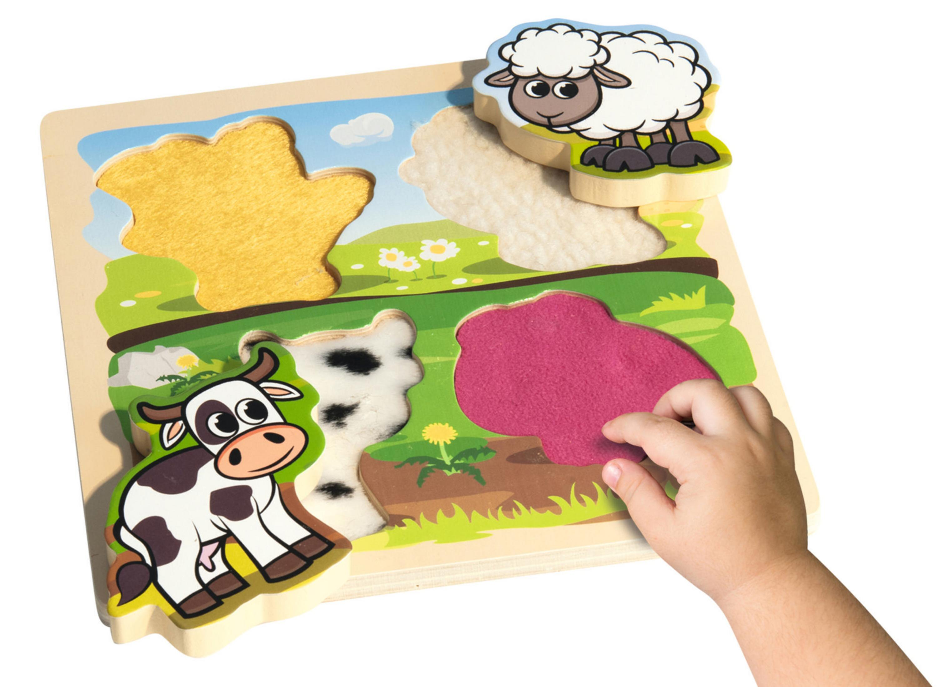 Kinderhand legt Filzteil auf Holz-Bauernhof-Tierpuzzle mit Kuh und Schaf.