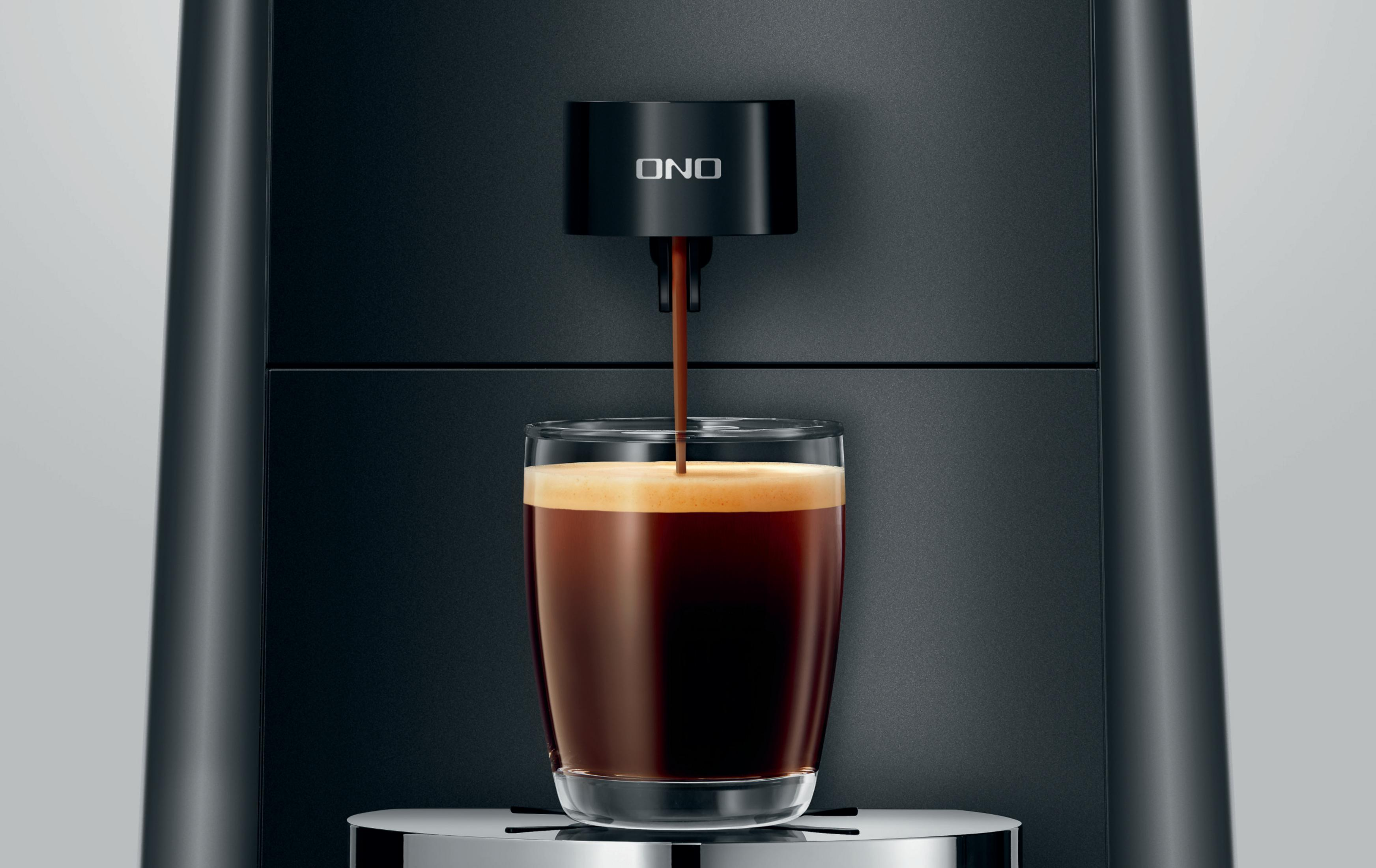 Schwarze Kaffeemaschine, die Kaffee in ein Glas gießt. Die Maschine hat ein ONO-Logo.