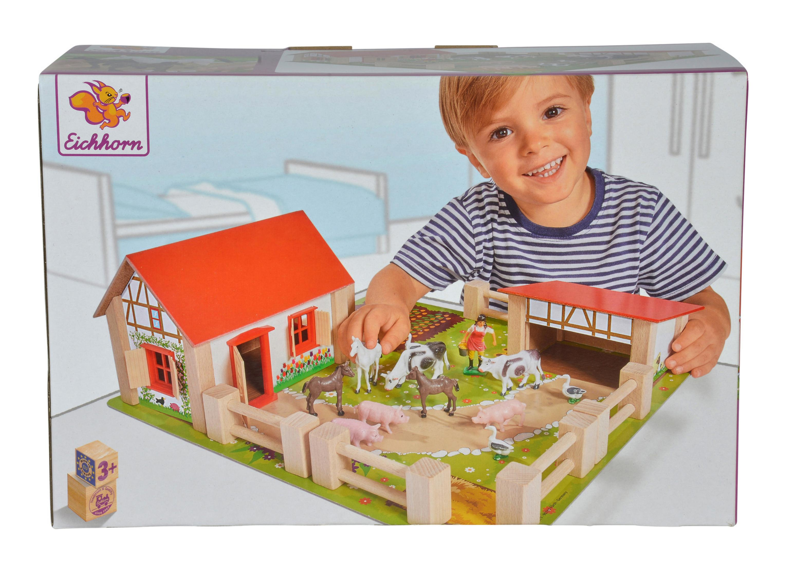 Dziecko z zestawem zabawek gospodarstwa. Zestaw zawiera dom, zwierzęta i ogrodzenia.