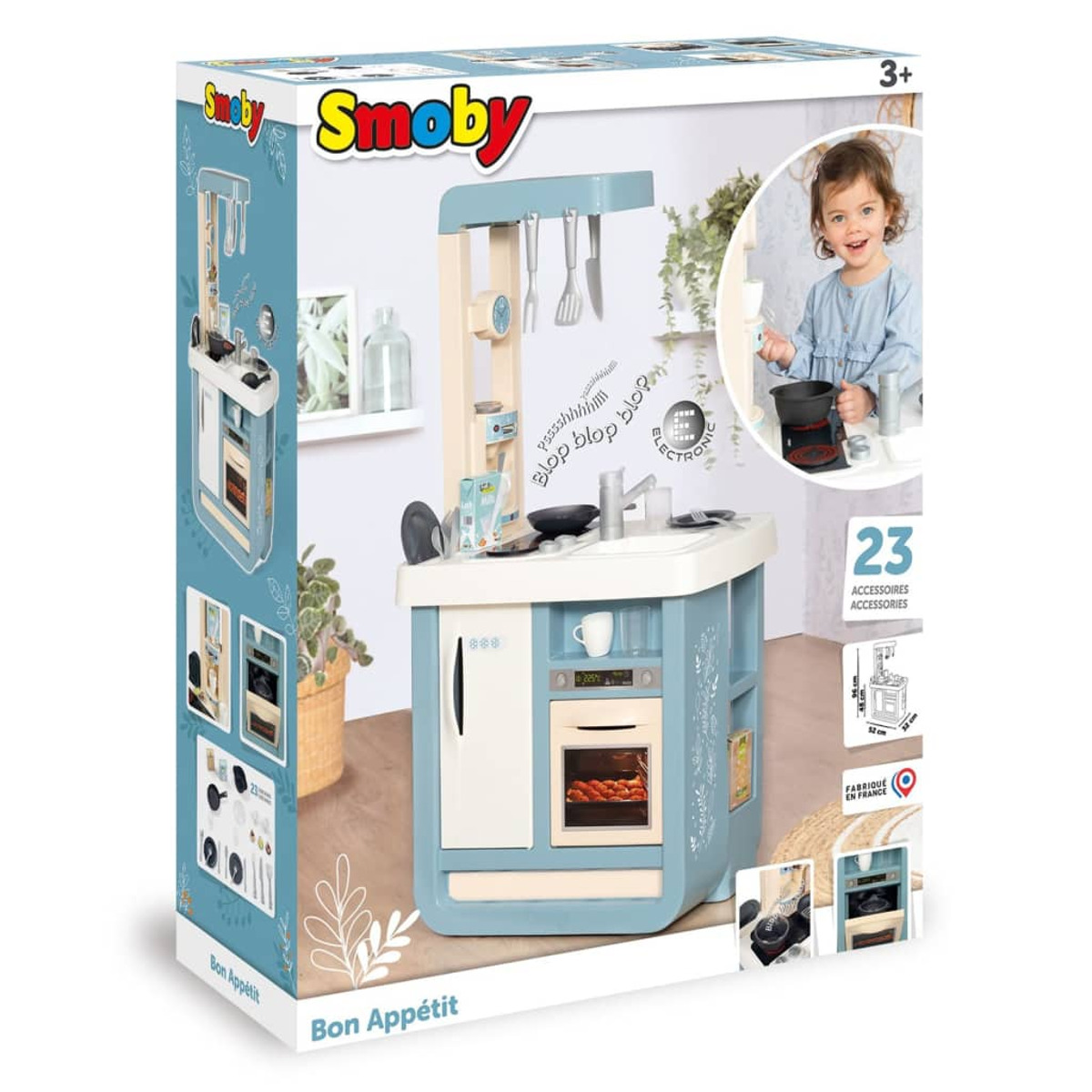 Zestaw zabawek kuchennych Smoby z dzieckiem bawiącym się w pobliżu, z różnymi akcesoriami.