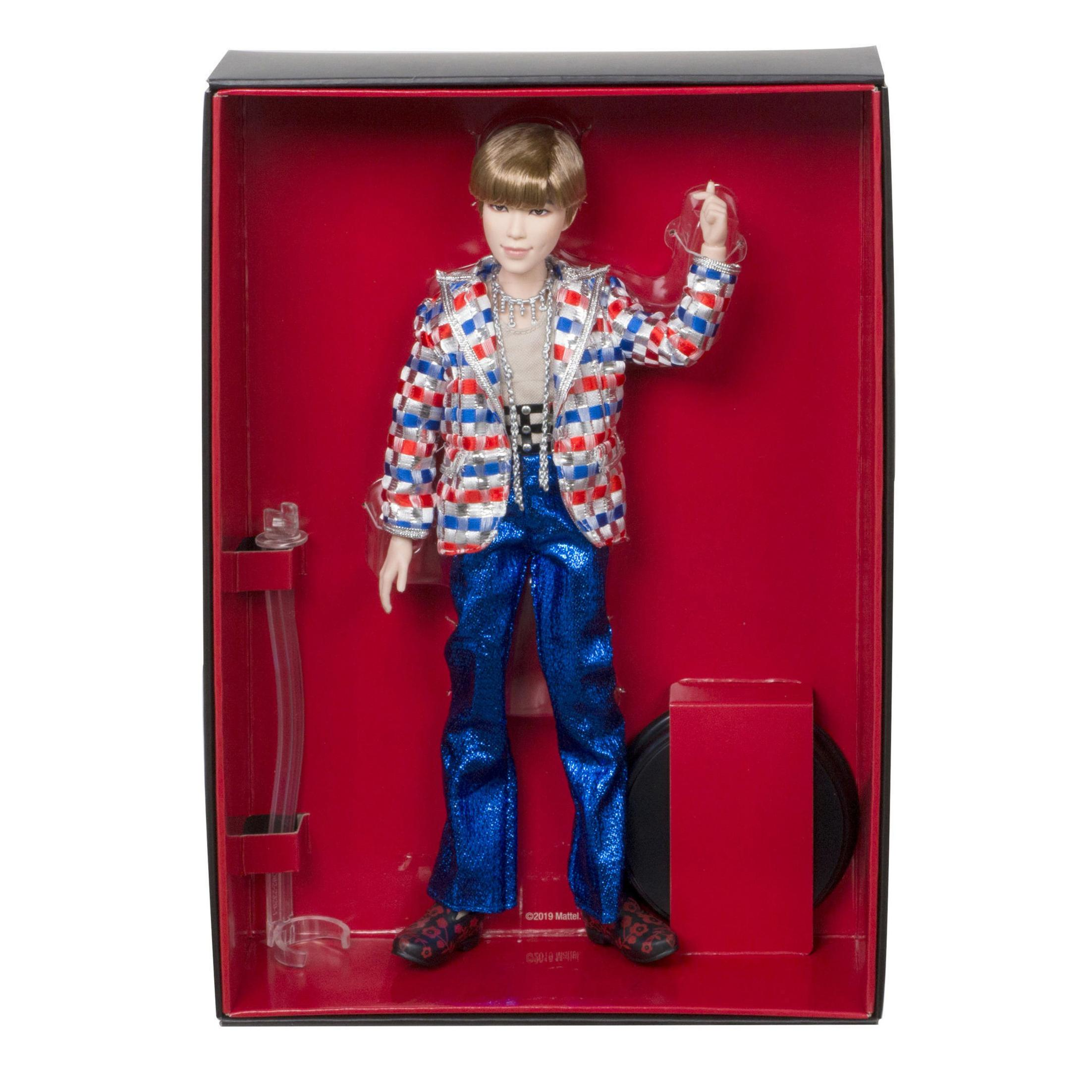 Eine Puppe in einem auffälligen Outfit in einer roten Box. Die Puppe hat eine Jacke.