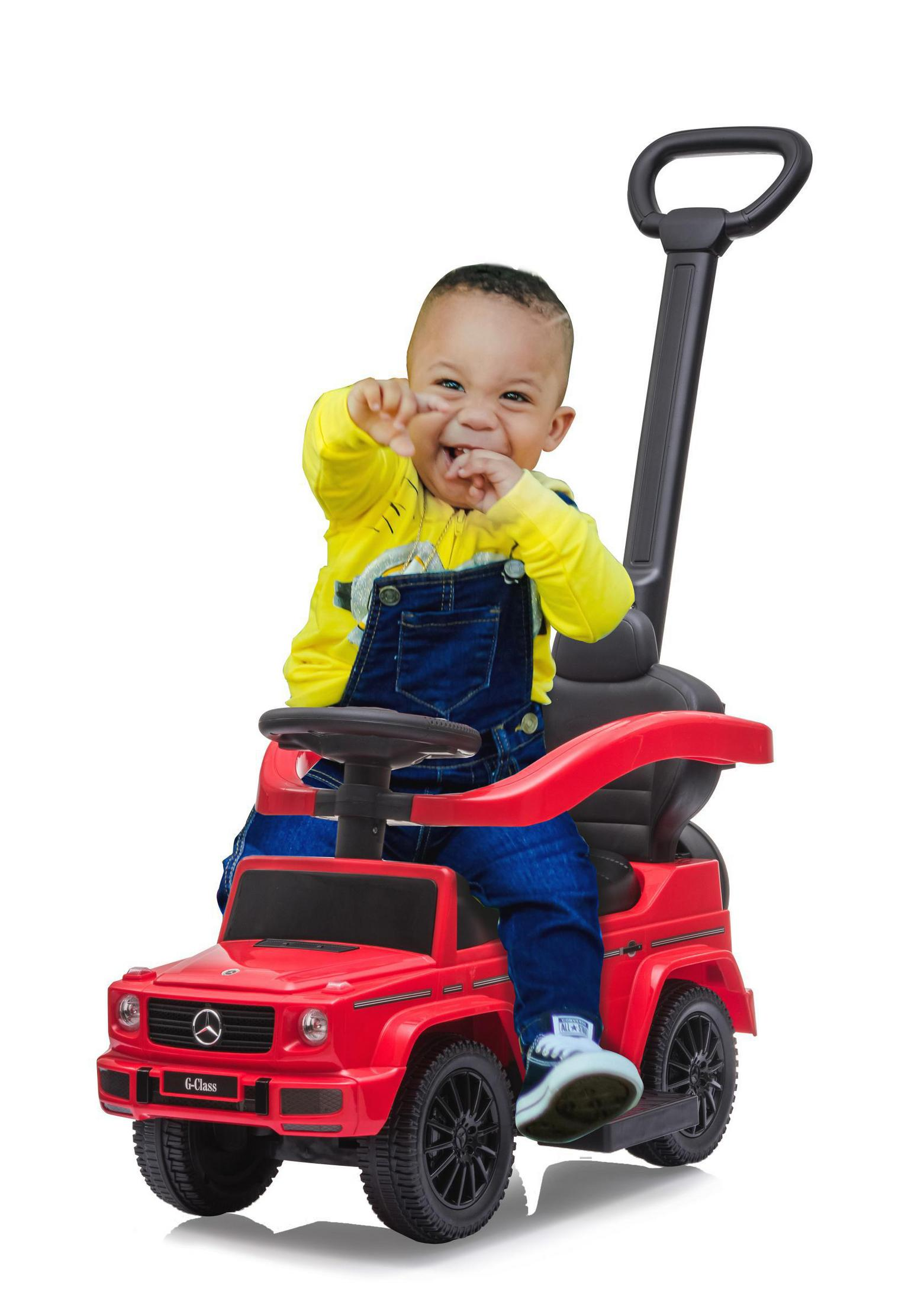 Ein Baby sitzt in einem roten Spielzeugauto. Er trägt ein gelbes Hemd und blaue Latzhosen.