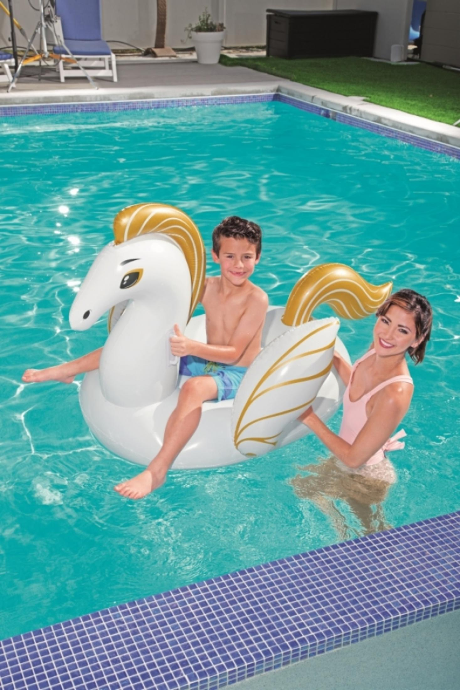 Zwei Kinder und eine Frau im Swimmingpool auf einem weißen und goldenen Einhorn-Schwimmtier.