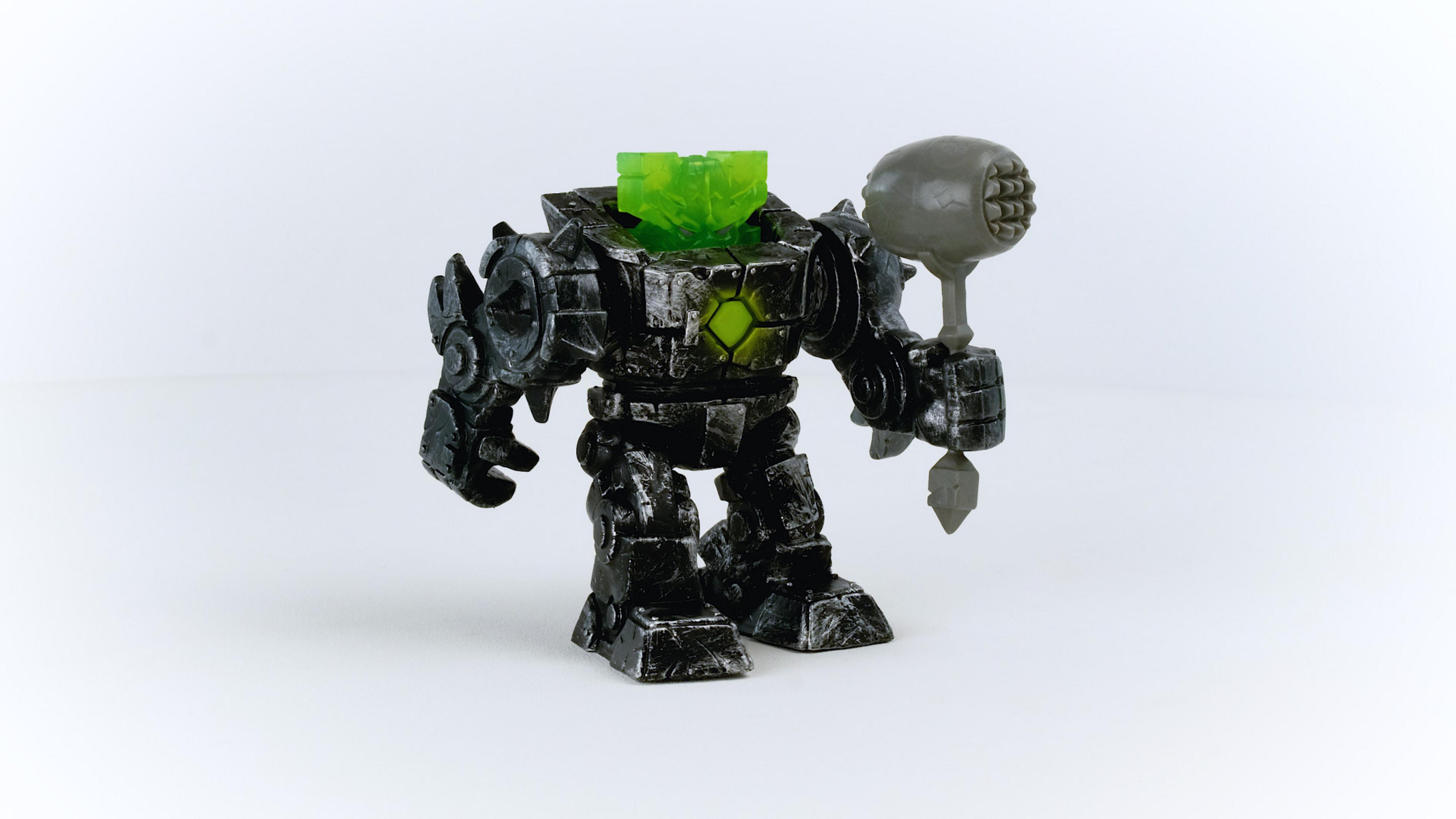 Robot giocattolo nero con testa verde. Tiene un martello grigio. Sfondo bianco.