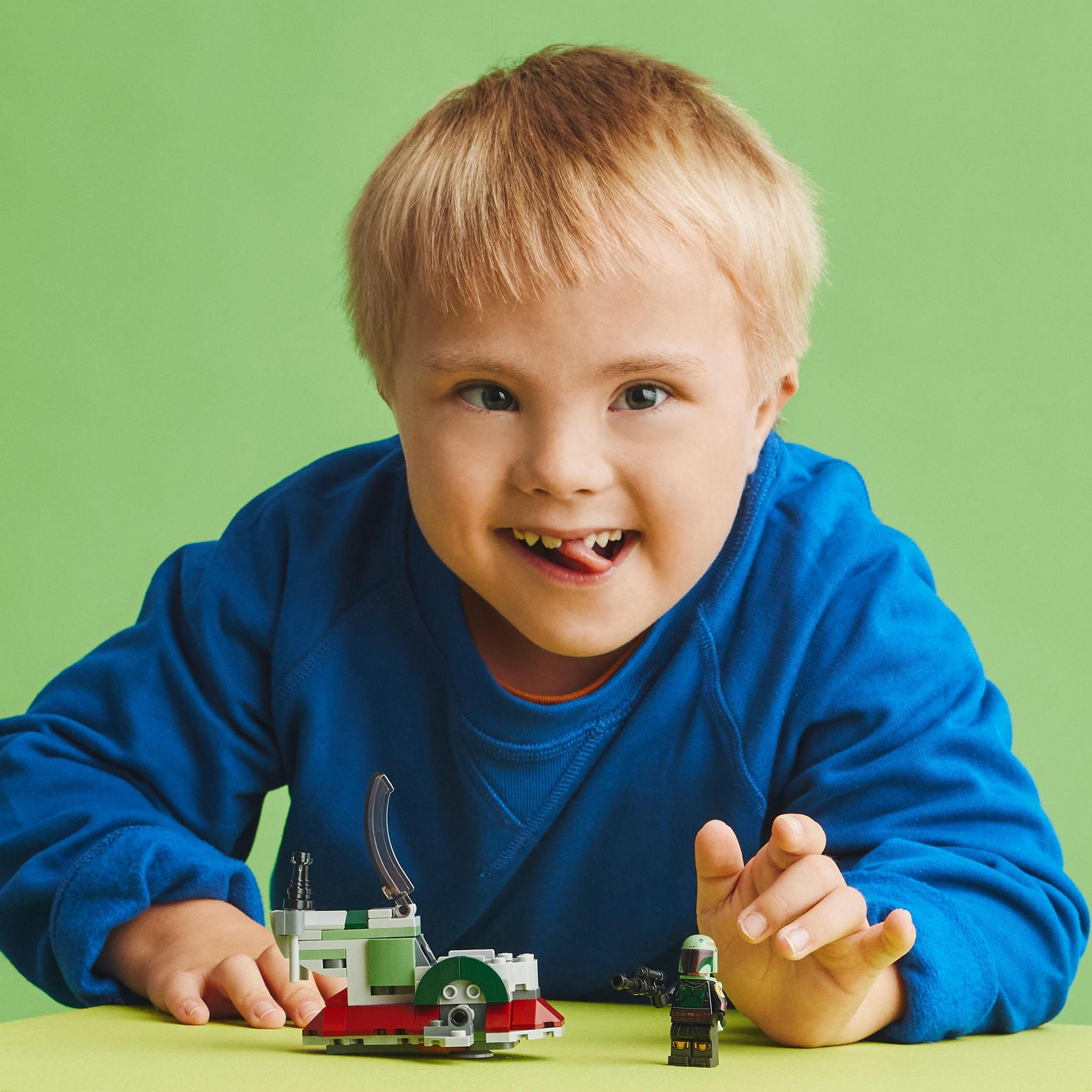 Un niño sonriendo, sosteniendo un set de Lego con una nave espacial y una figura.