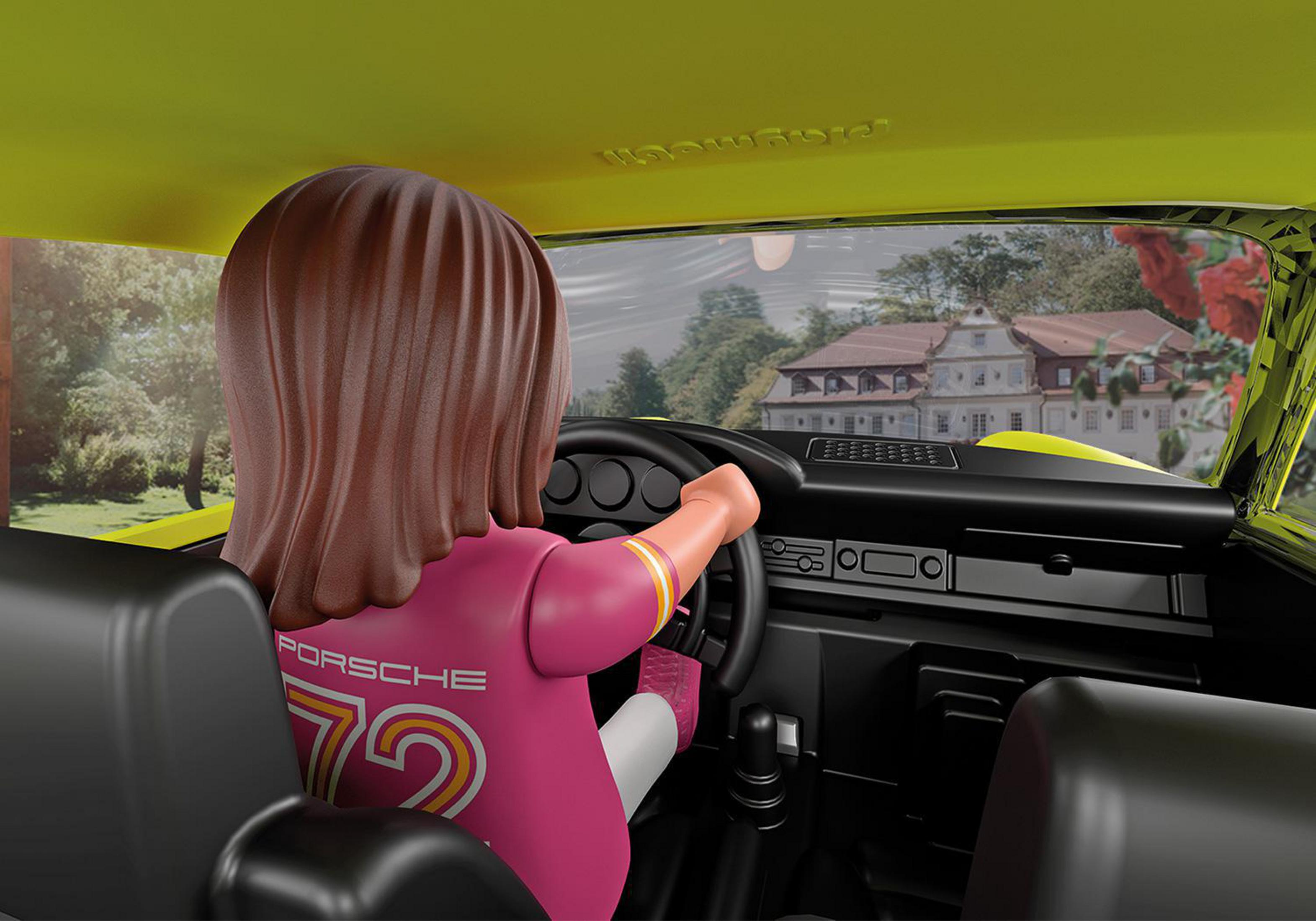 Eine Person in einem rosa Hemd fährt einen gelben Porsche Spielzeugwagen. Landschaftlicher Hintergrund.