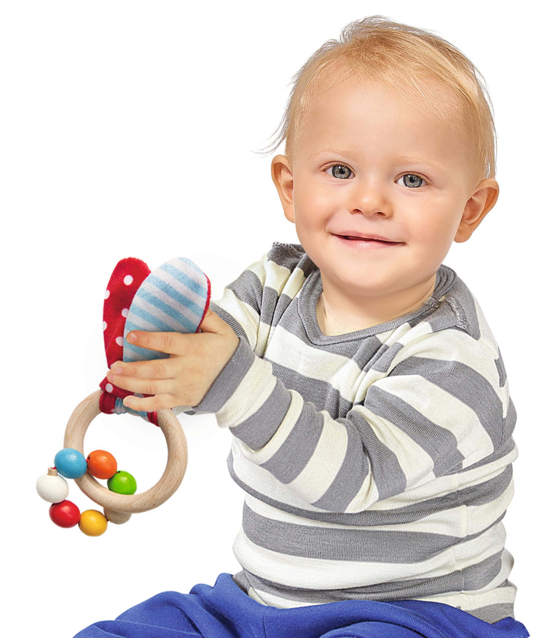 Ein lächelndes Baby hält ein Holzring-Spielzeug mit bunten Perlen.