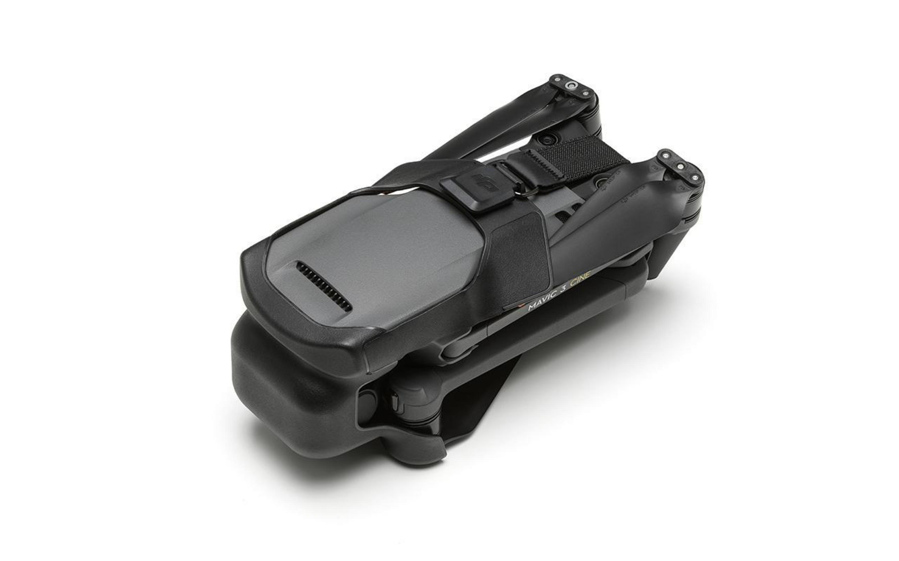 Drone noir plié avec une sangle noire. Fond blanc.