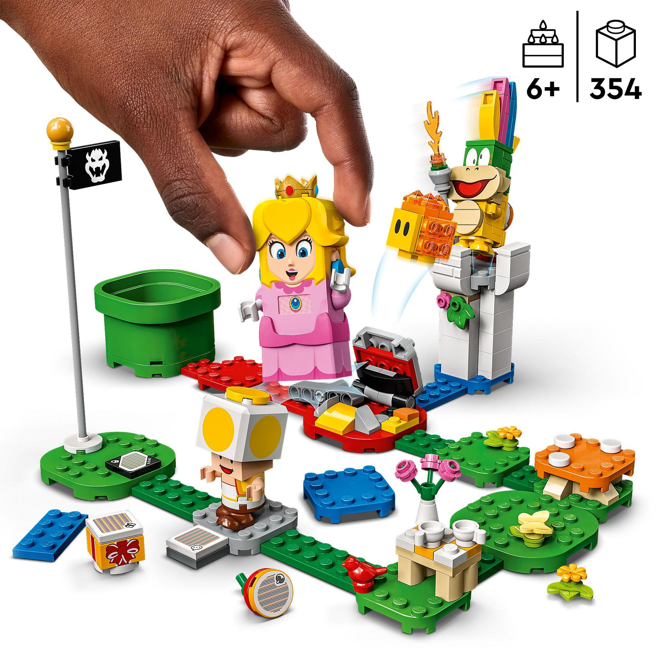 Lego Super Mario set. Een hand plaatst een figuur op een groene basis met andere figuren en accessoires.