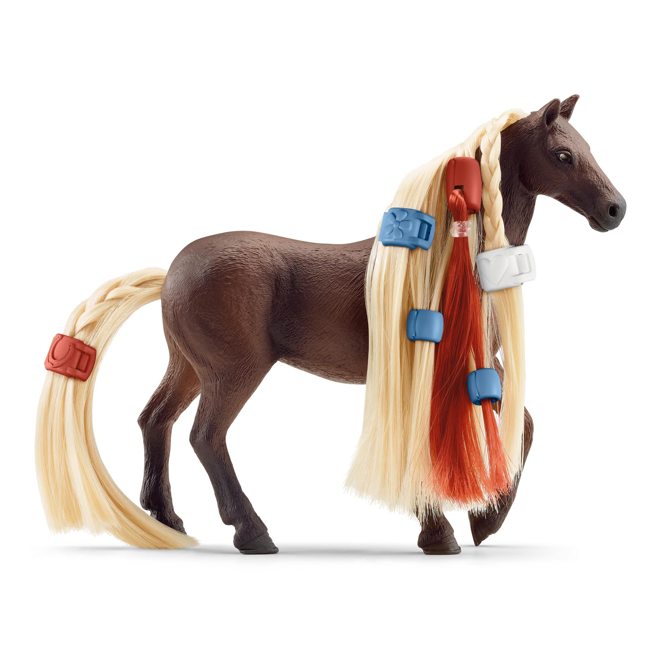 Spielzeugpferd mit blonden Mähne und Schweif, verziert mit farbigen Haaraccessoires, auf Weiß.