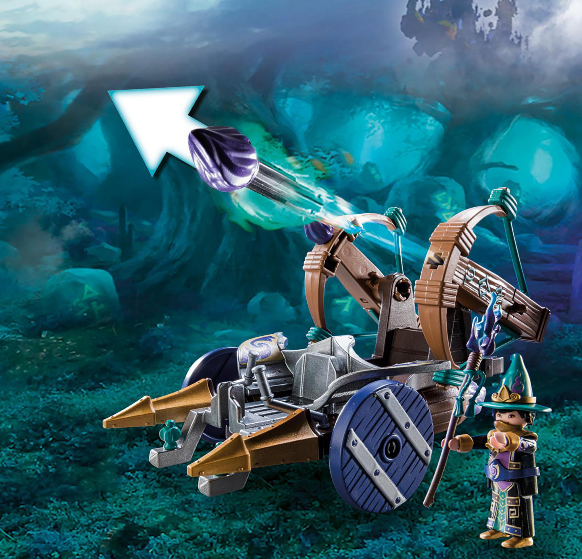 Playmobil-Zauberer mit einer Katapult, die ein lila Geschoss abfeuert. Grüner und blauer Hintergrund.