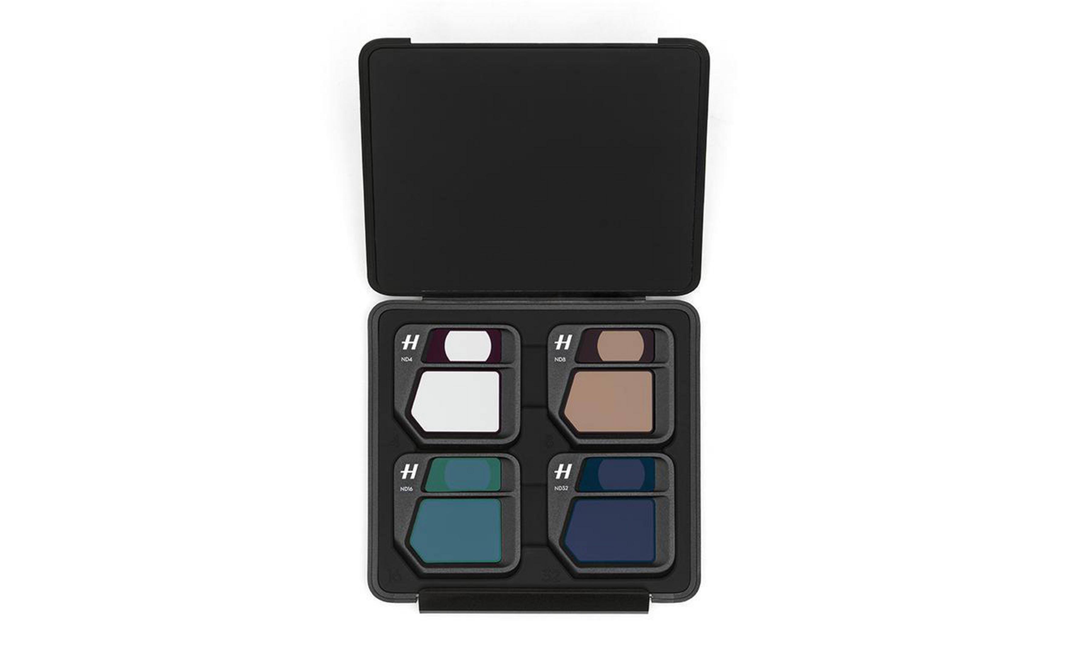 Un estuche negro que contiene cuatro filtros de cámara. Los filtros son de varios colores, con fondos blancos.