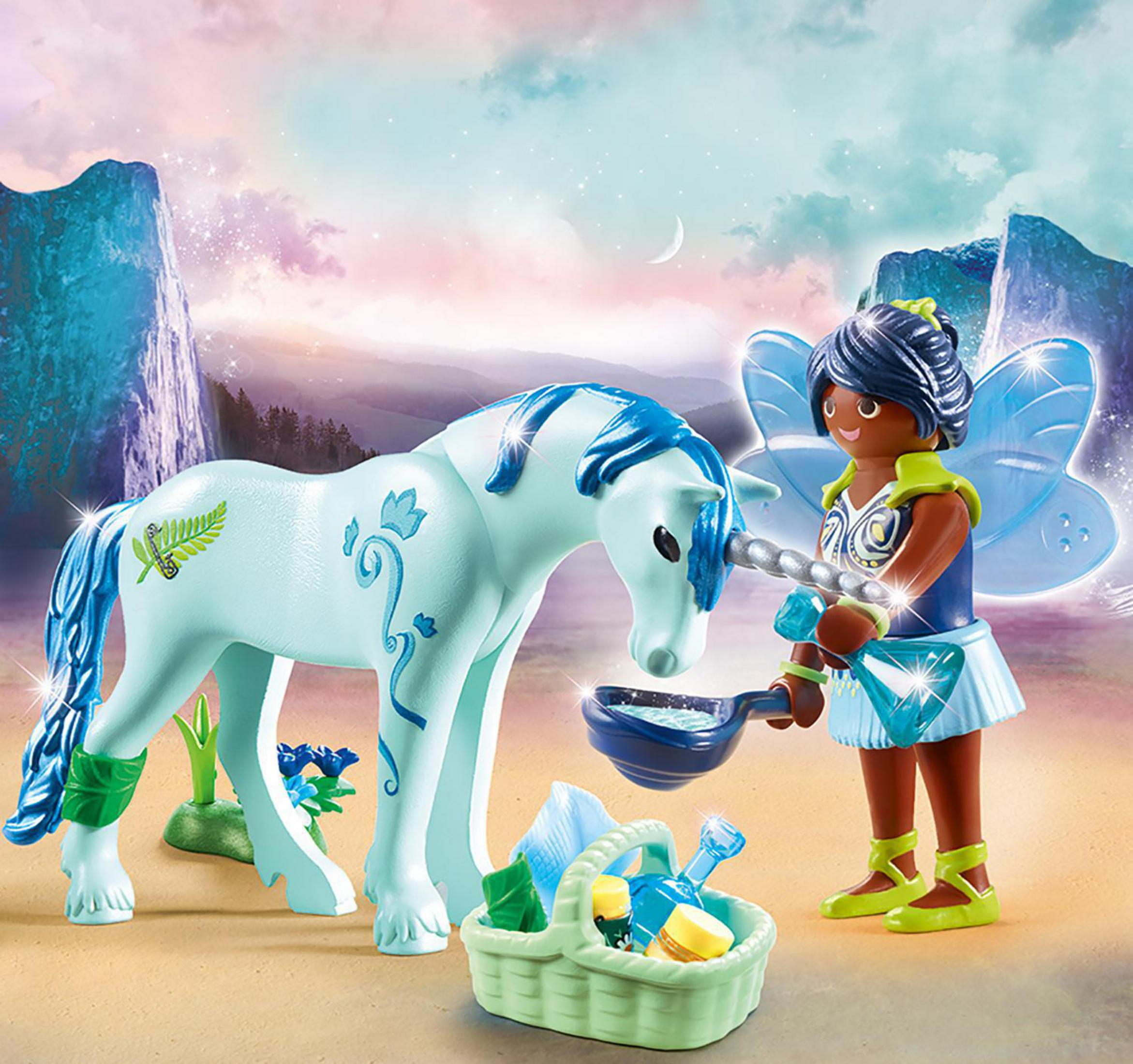 Eine Feenfigur füttert ein weißes Einhorn mit einem Korb voller Spielzeug. Berge im Hintergrund.