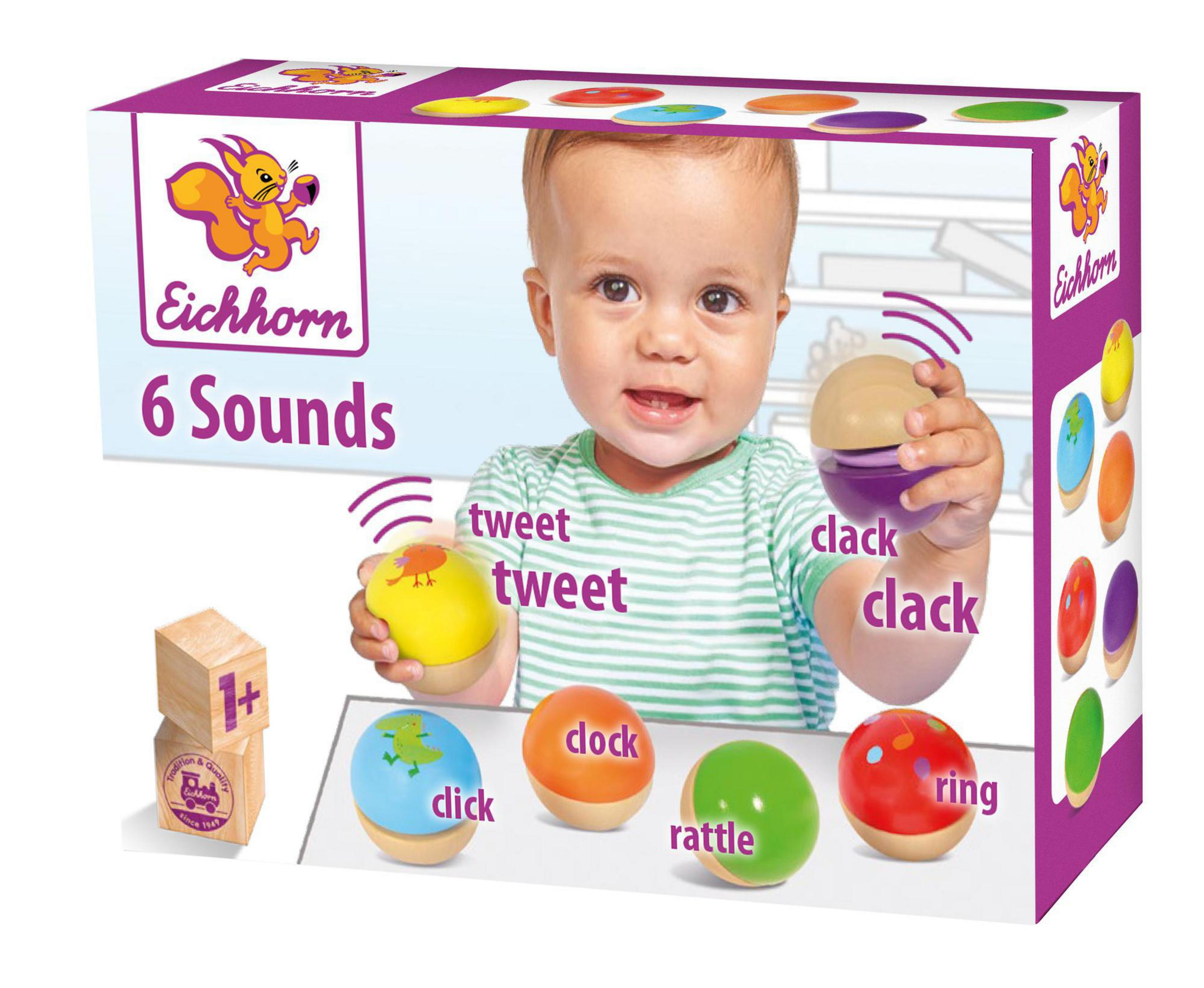 Ein Baby mit Spielzeug. Das Spielzeug macht Geräusche. Im Hintergrund eine Box mit weiterem Spielzeug.