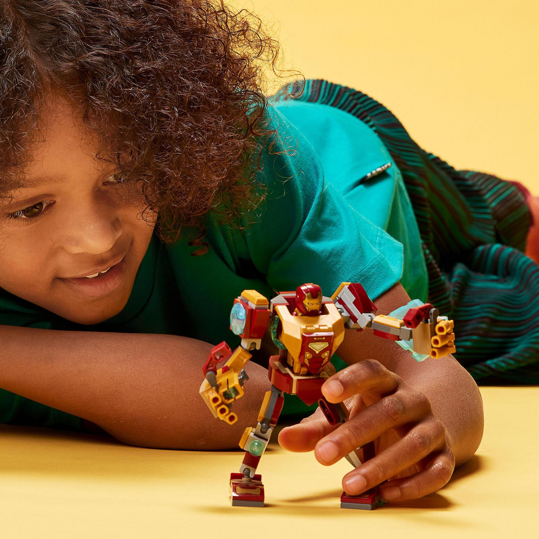 Un bambino che gioca con un giocattolo Lego di Iron Man, sfondo giallo, espressione gioiosa.