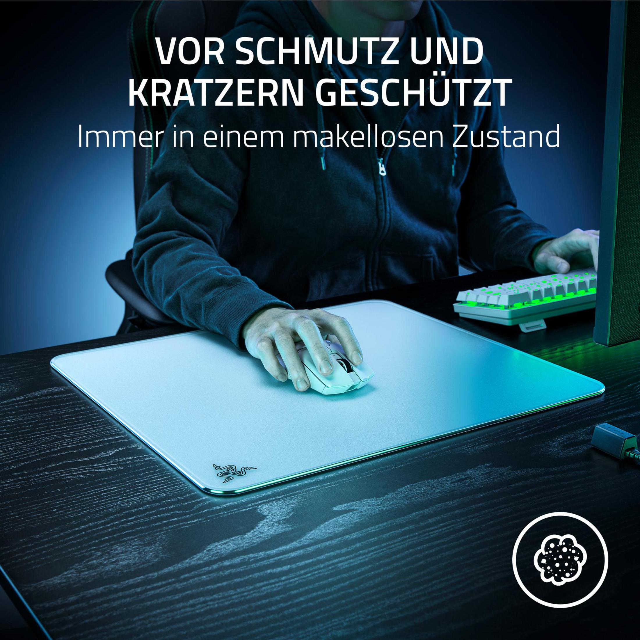Osoba używa białej myszy na białej podkładce. Tekst brzmi 'Vor Schmutz und Kratzern geschützt'.
