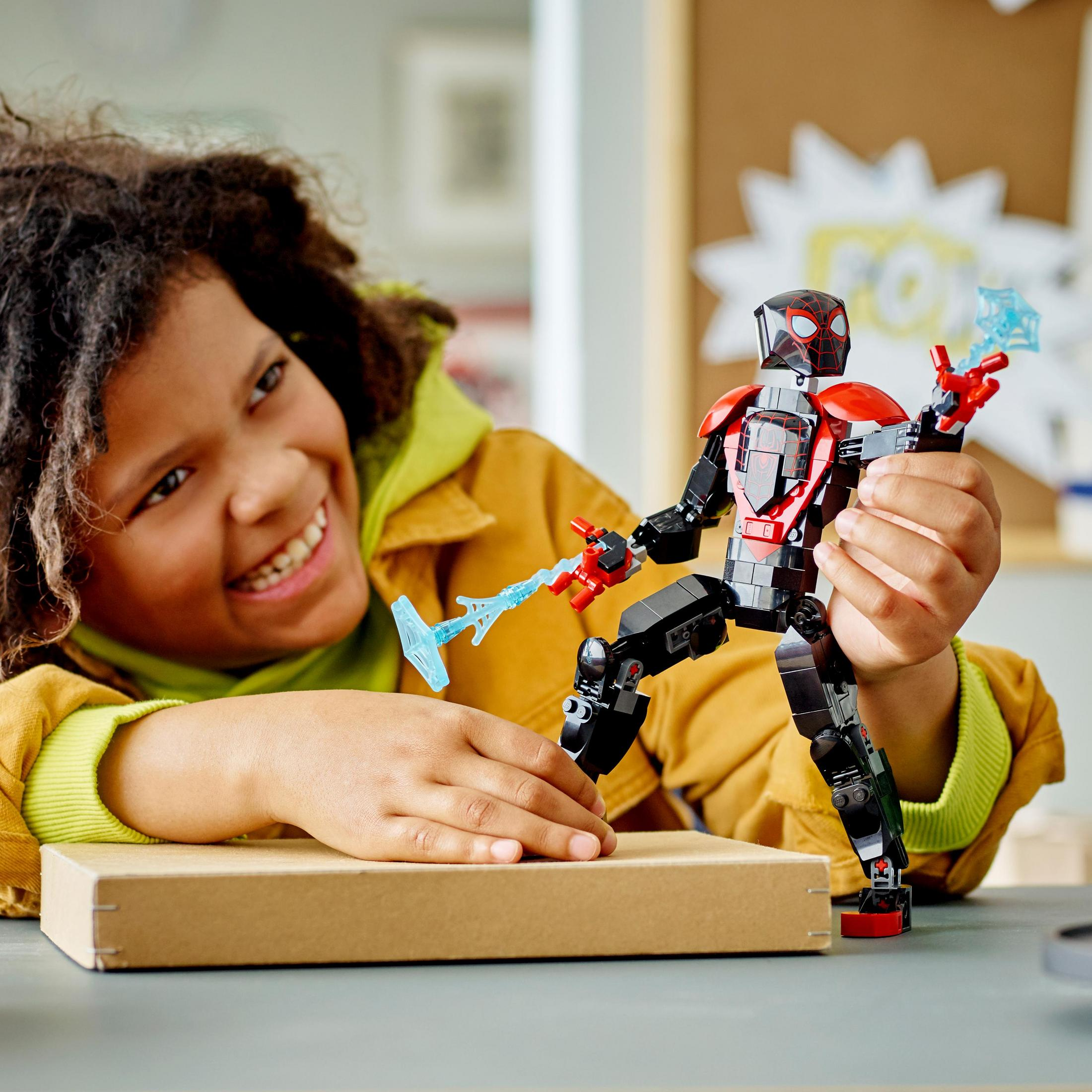 Ein Kind spielt mit einer Lego Spider-Man Figur. Ein Pop-up-Cartoon-Hintergrund.