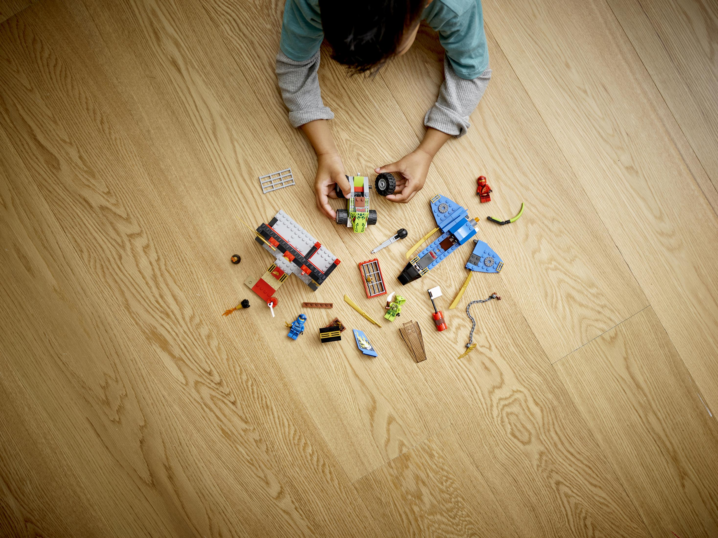 Ein Kind spielt mit verschiedenen LEGO-Teilen auf einem Holzboden. Die LEGOs sind verstreut.