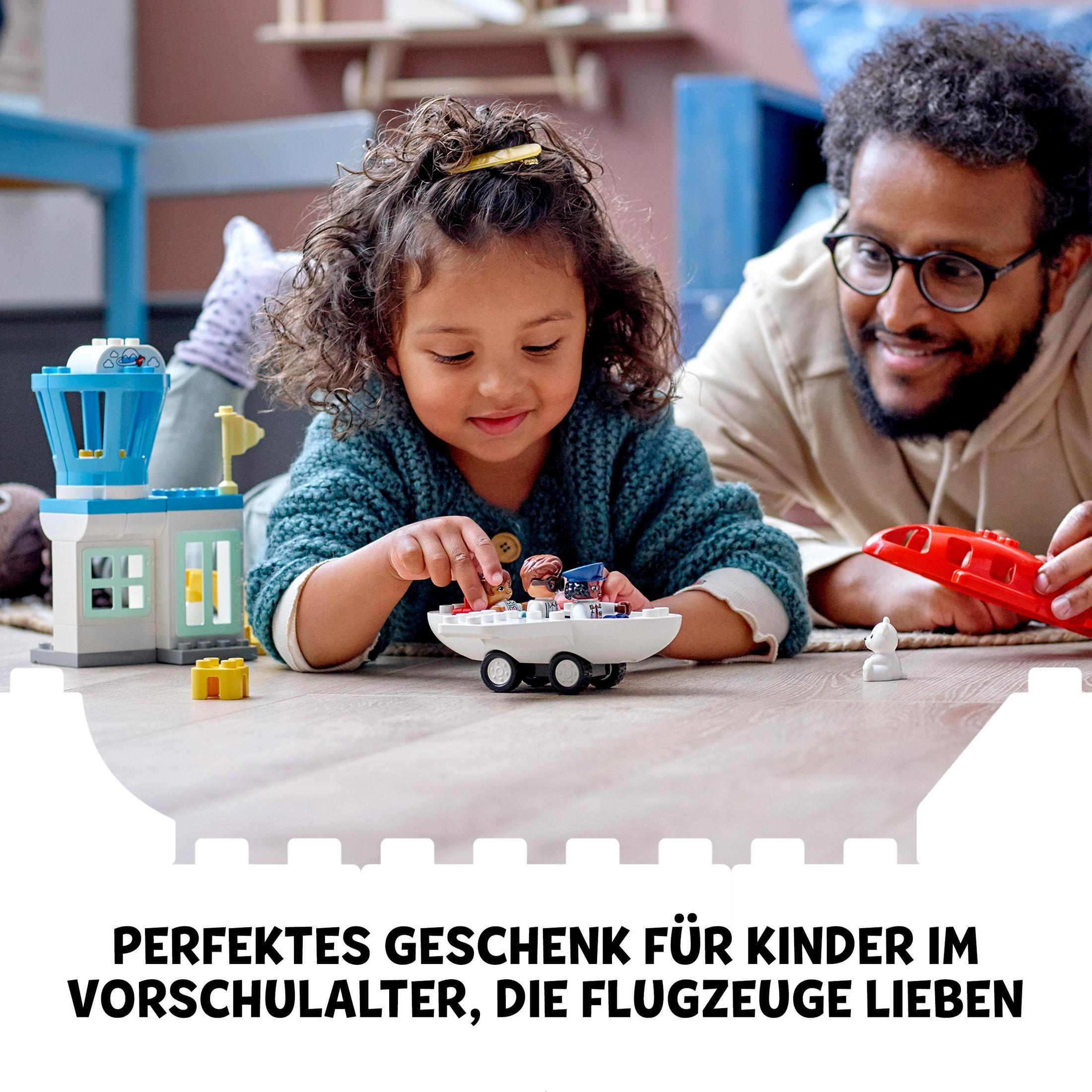 Ein Kind und ein Mann spielen mit einem Spielzeugflugzeug und LEGO-Flughafengebäude.